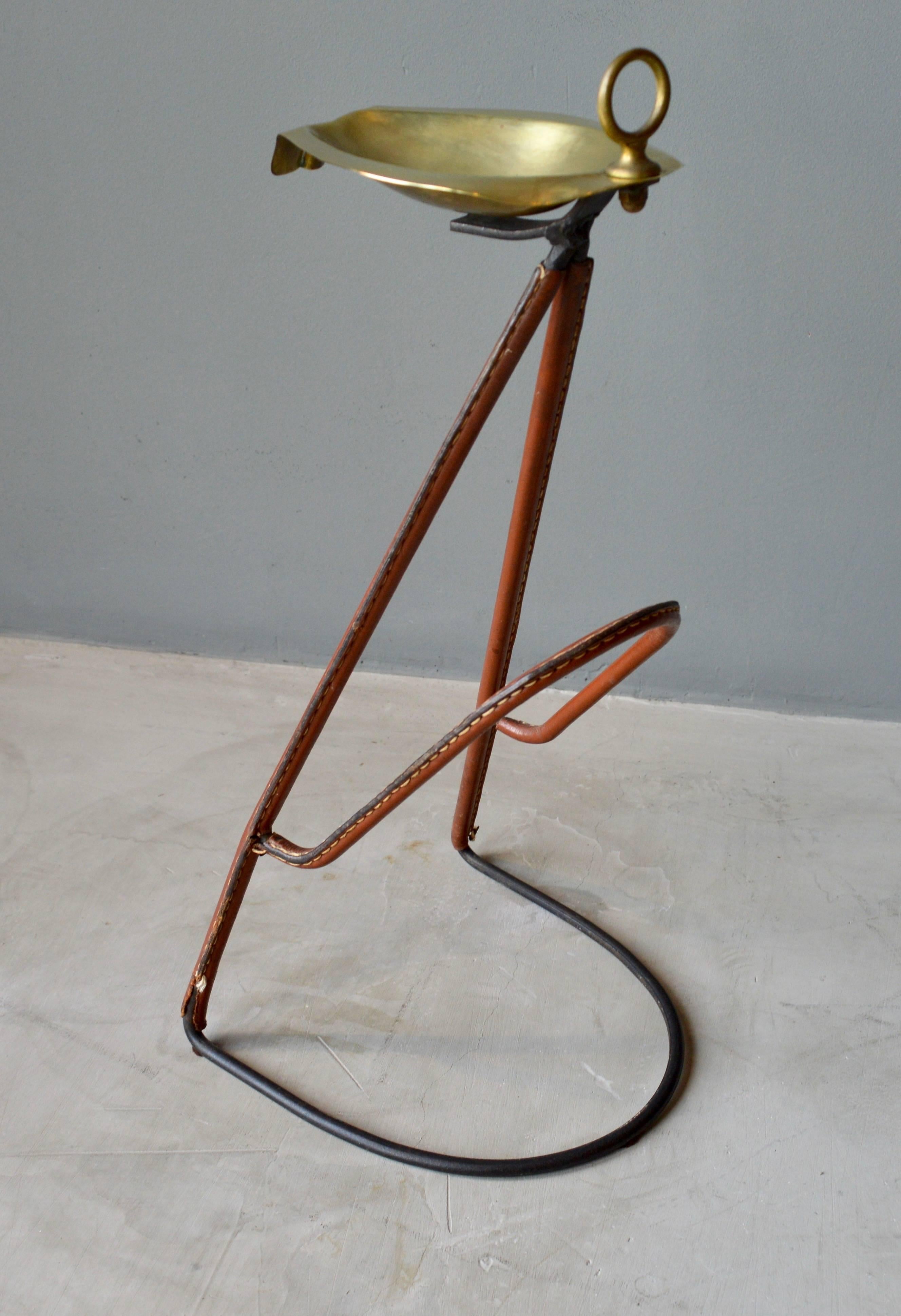 Unique iron and leather magazine rack / ashtray by Jacques Adnet. Iron base and frame with saddle leather wrapped throughout. Great patina to leather. Brass dish on top. Very unique Adnet piece.