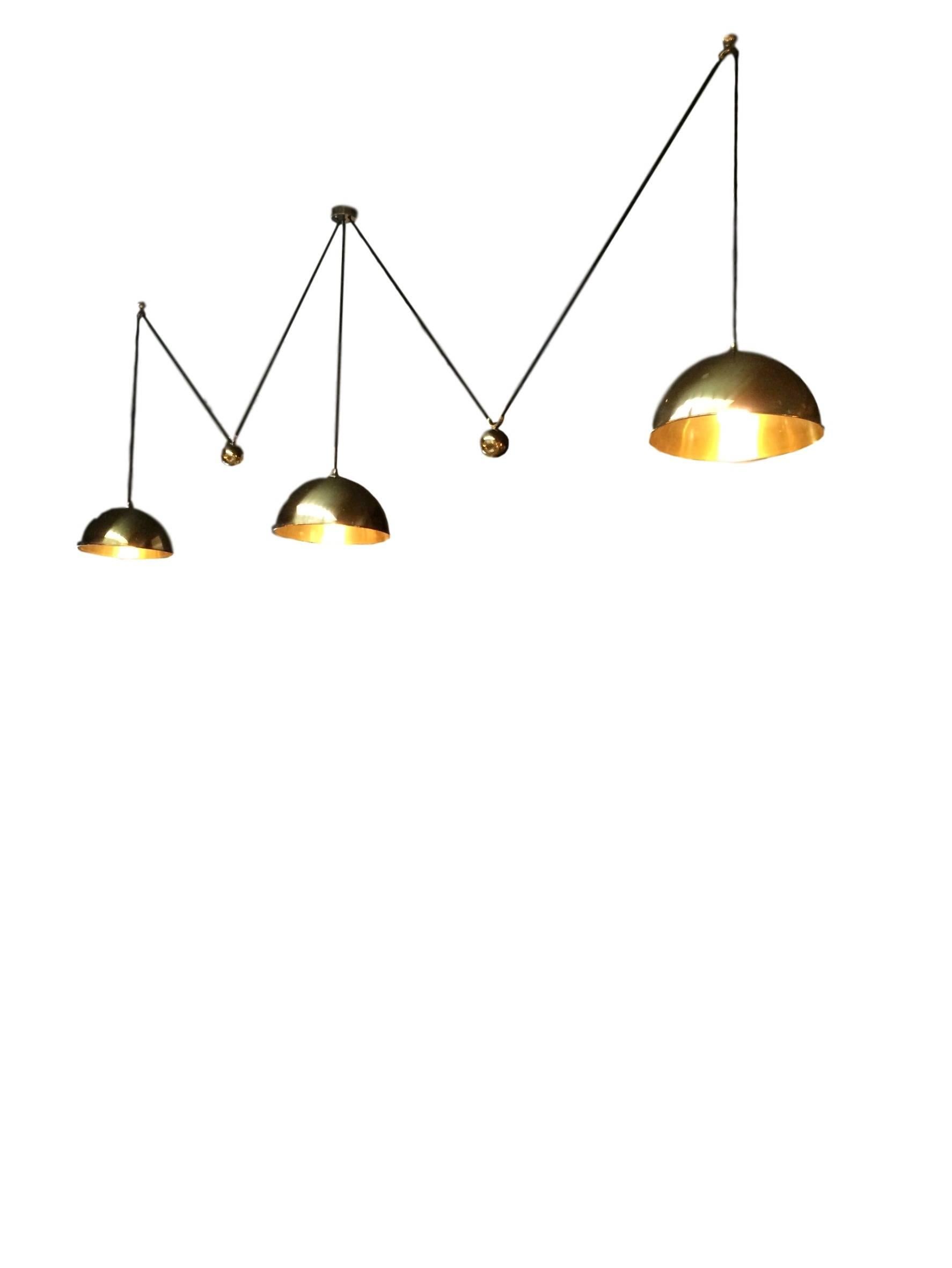 Extremely rare triple counter balance pendants by Florian Schulz. Three brass domes with brass counter weights, canopy and hardware. Black cloth cord. Center brass pendant is manually adjusted to the desired height and held by a set screw inside the