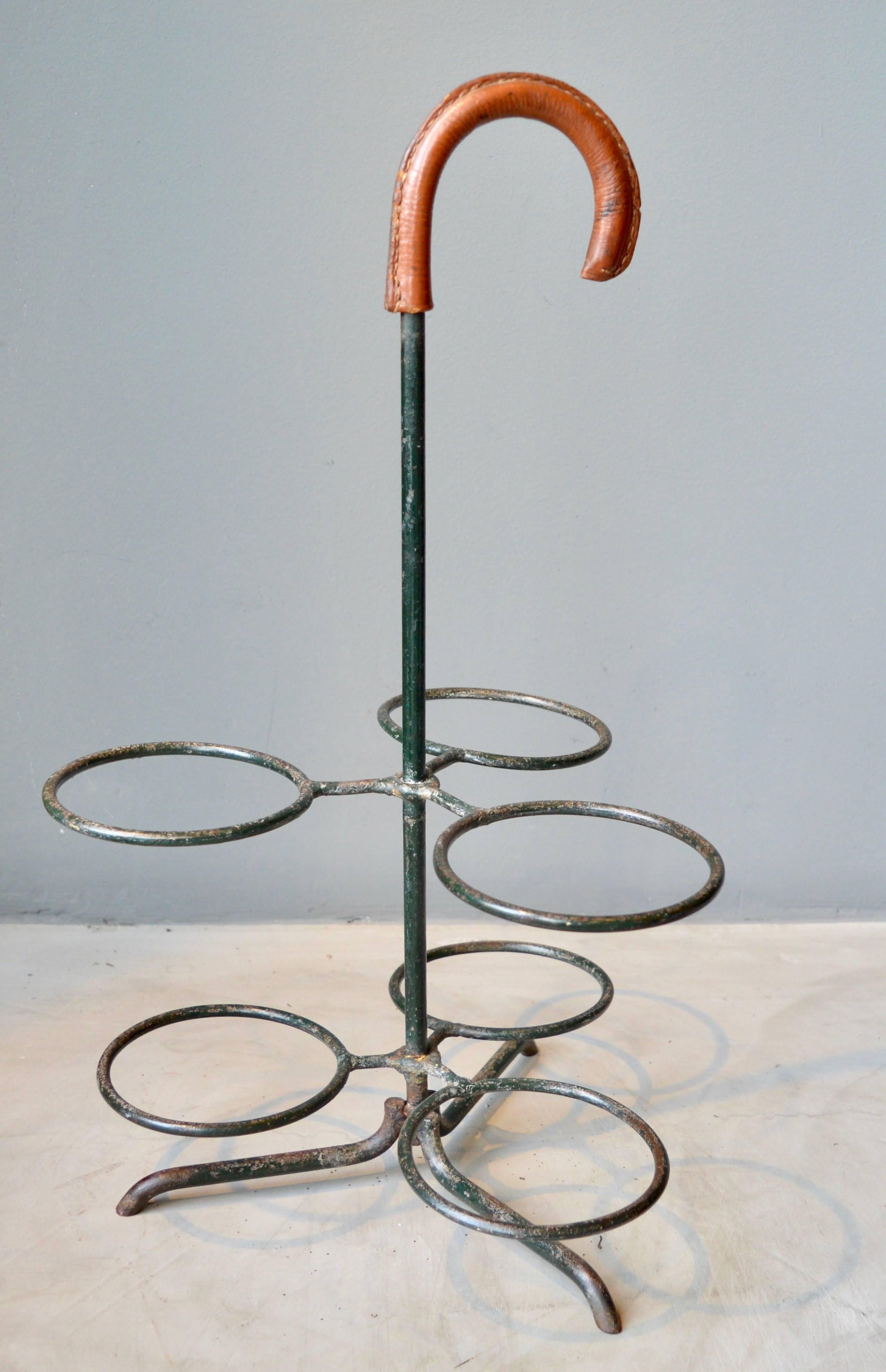 Handsome three bottle wine holder or umbrella stand by Jacques Adnet. Iron frame with saddle leather handle. Signature Adnet contrast stitching. Great patina to leather and iron. Excellent vintage condition.