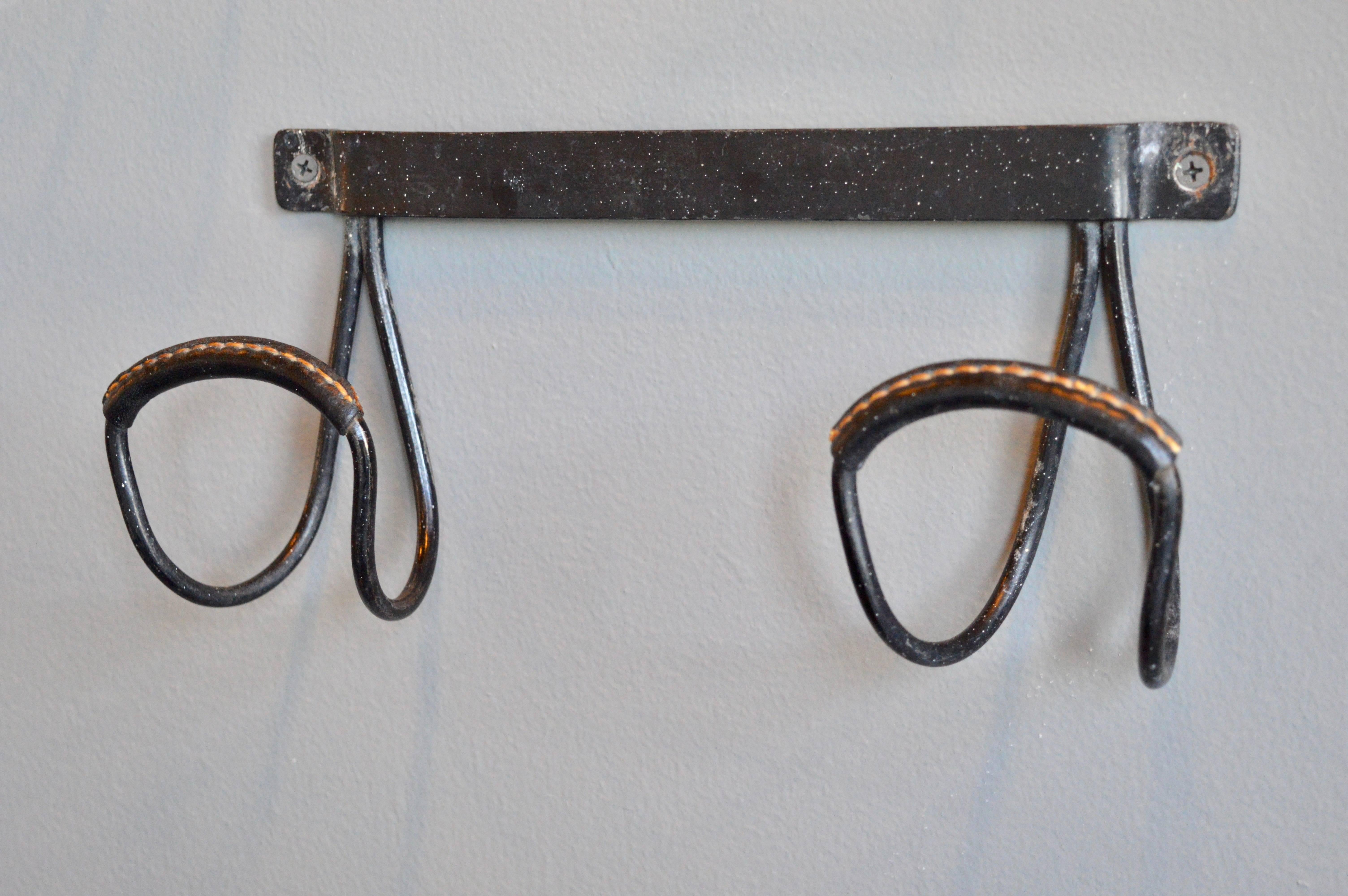 Handsome coat hook by French designer Jacques Adnet. Iron frame with leather wrapped hooks. Black leather with signature contrast stitching. Excellent vintage condition.
