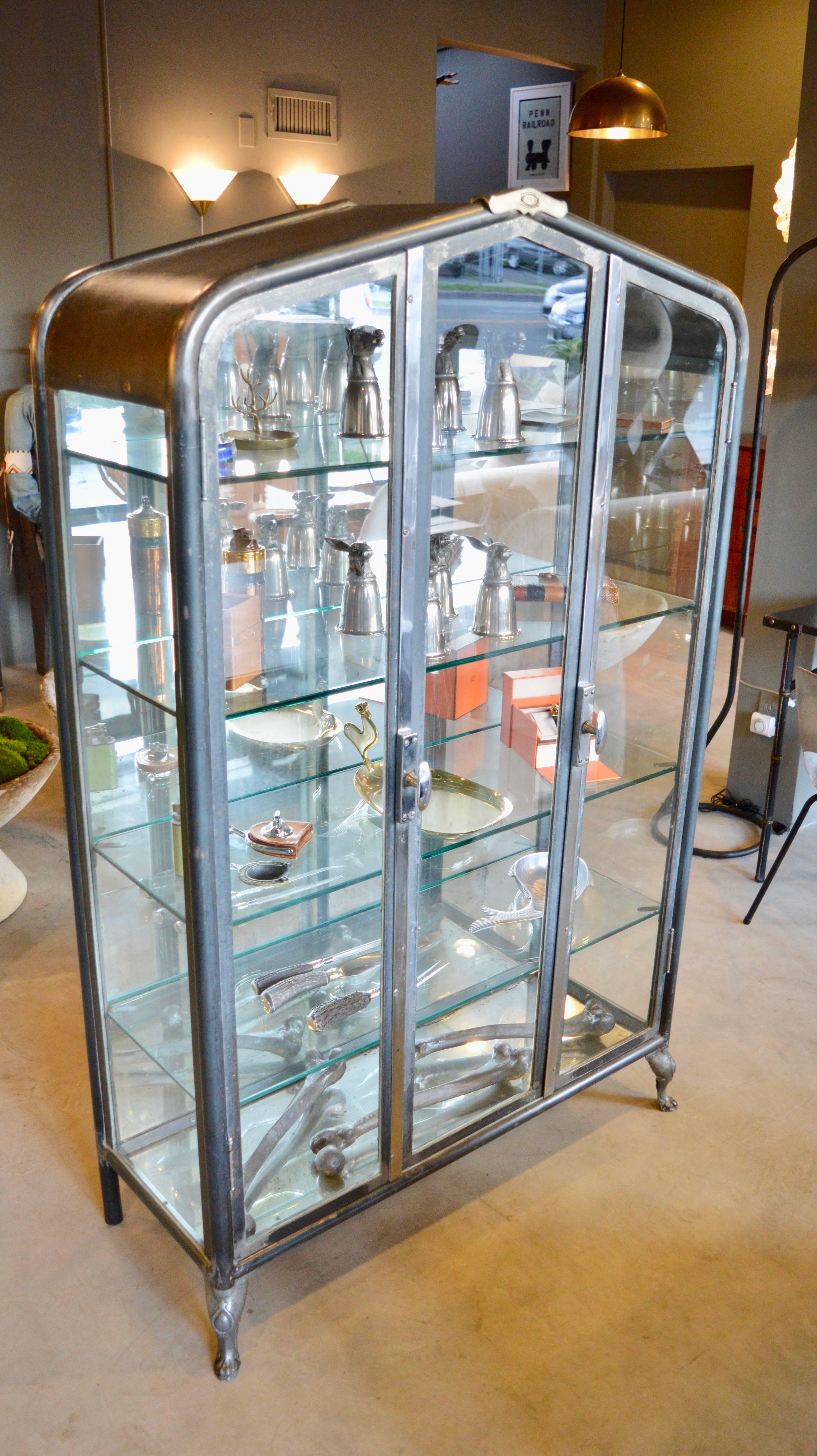 Incredible metal and glass vitrine from Argentina, circa 1930. Marked "ECYCA" Impressive shape and design. Very sturdy and heavy. In excellent condition. All original glass frame with newly made glass shelves. Two doors open on either side