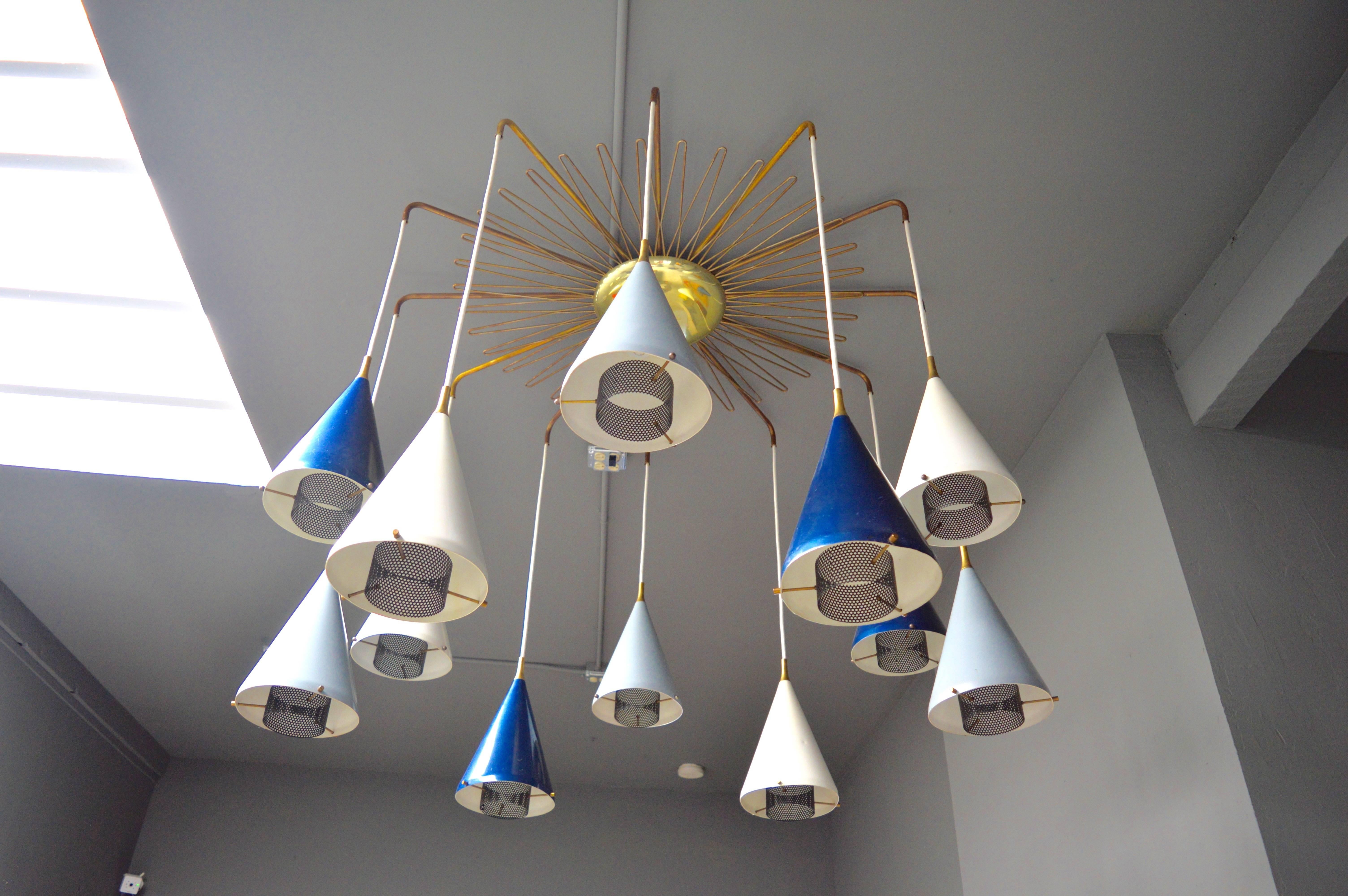 Extremely unique chandelier in the style of Mathieu Matégot. 12 painted metal cones with perforated metal diffusers and brass hardware, suspend from brass arms, brass canopy and brass starburst frame. Looks amazing both on and off. Great design and