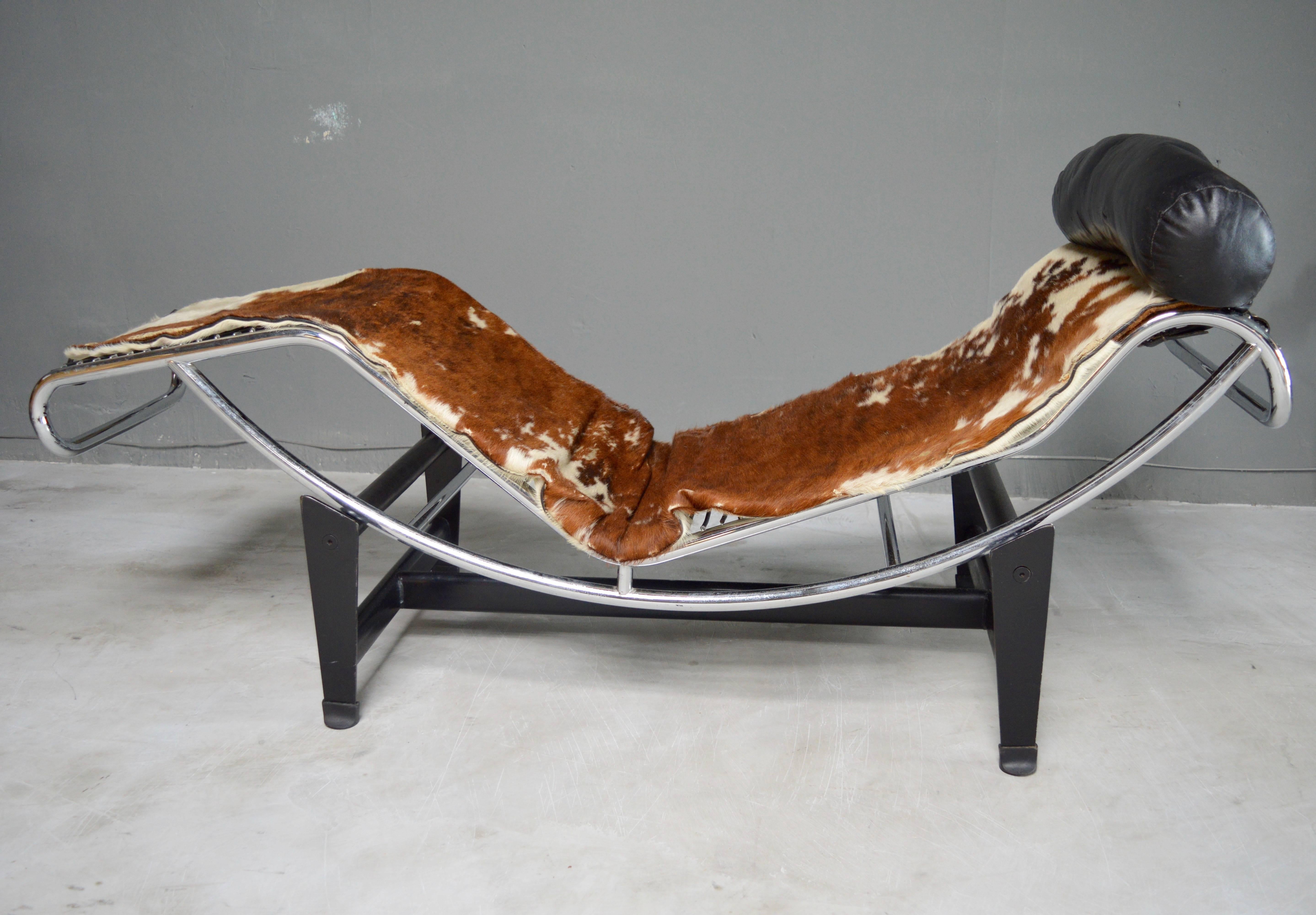 Lounge chair in the style of classic Le Corbusier. Black metal base with chrome tubular, adjustable lounge chair. Cowhide seat with leather headrest. Good vintage condition. Iconic chair.