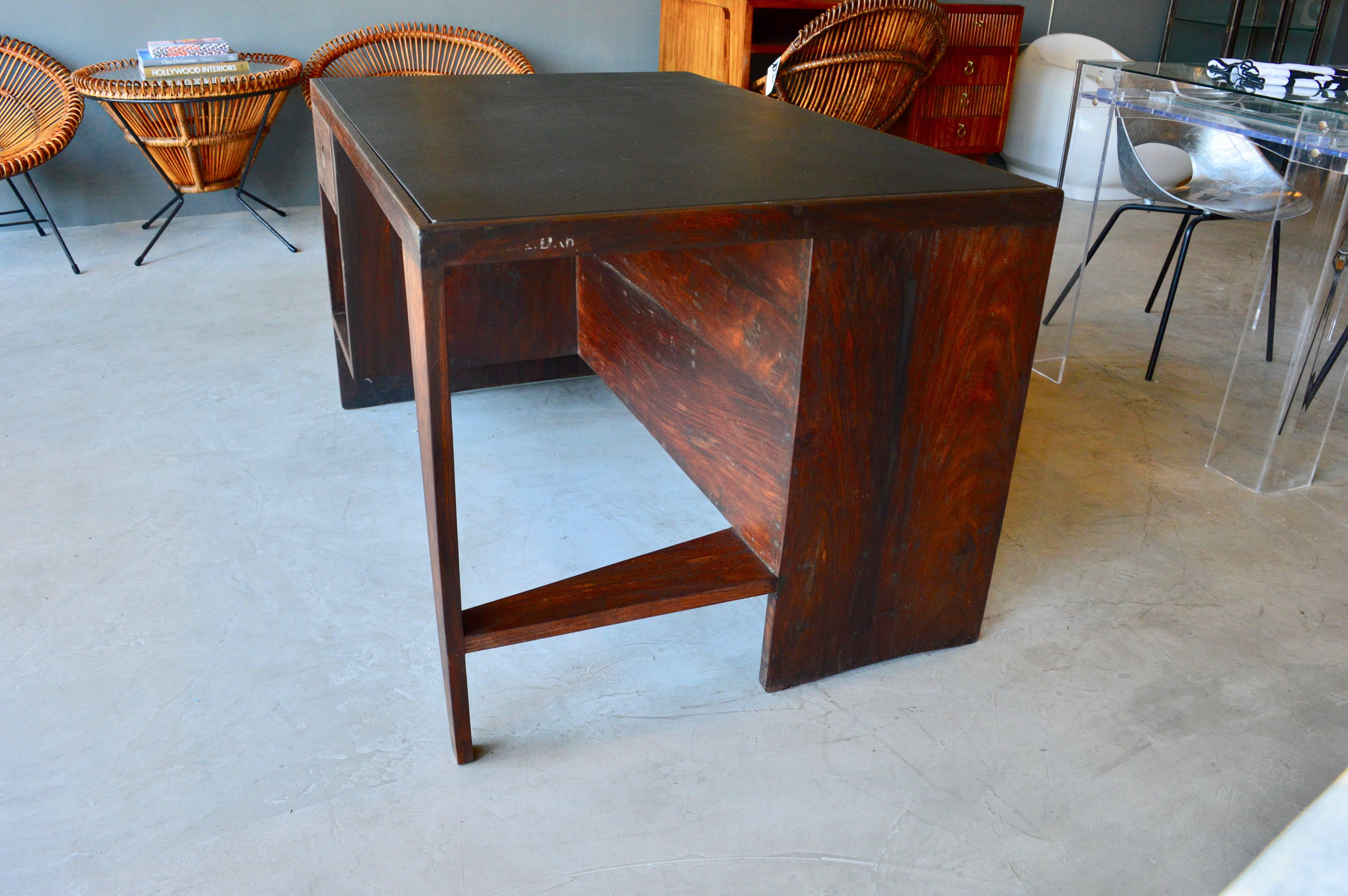 Stunning desk in Rosewood by Pierre Jeanneret. Made for the Chandigarh project. Angular leg and bookcase back. One of the most iconic pieces of modern design. Black leather top. Desk in excellent vintage condition. 

Jeanneret Library chair