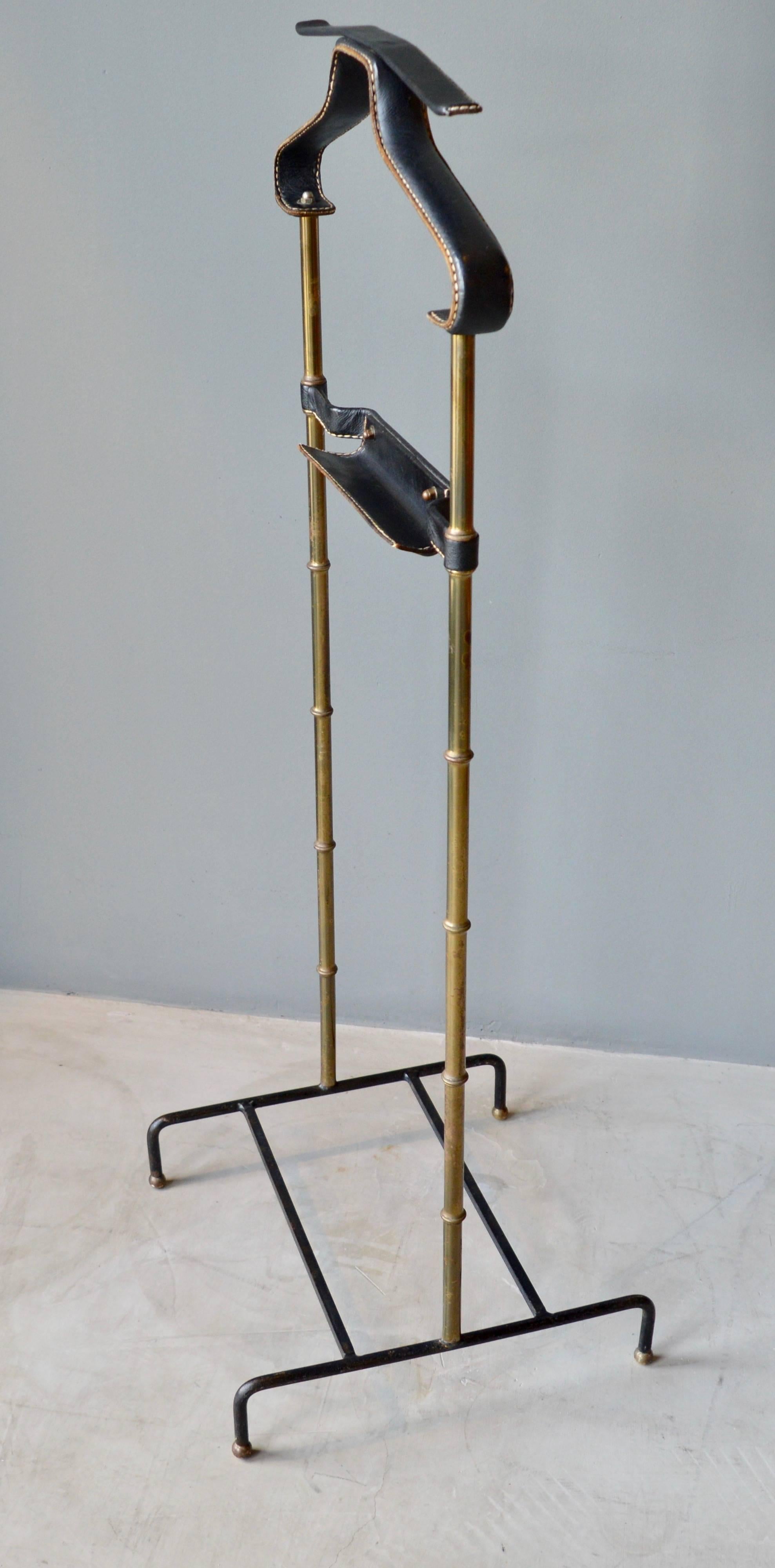 Handsome coat stand or valet by Jacques Adnet. Valet has an iron base, brass bamboo frame and leather wrapped catch all and coat/pant holder. Leather has signature Adnet contrast stitching. Excellent vintage condition. An all black Adnet leather