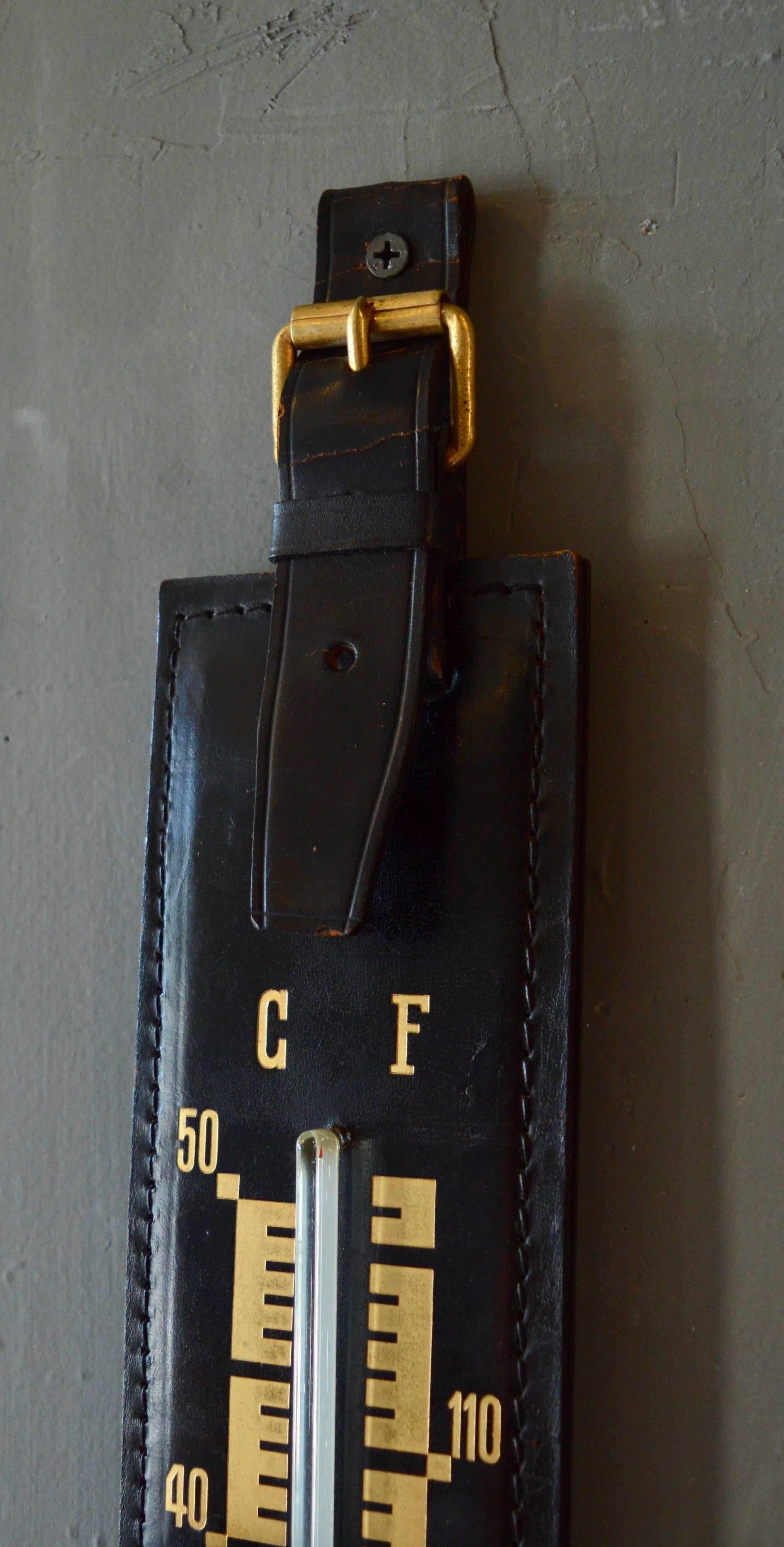 Handsome leather wall thermometer in the style of Jacques Adnet. Black leather with brass detailing. Temperature displayed in Celsius and Fahrenheit. Excellent vintage condition. Seems to be in perfect working order.