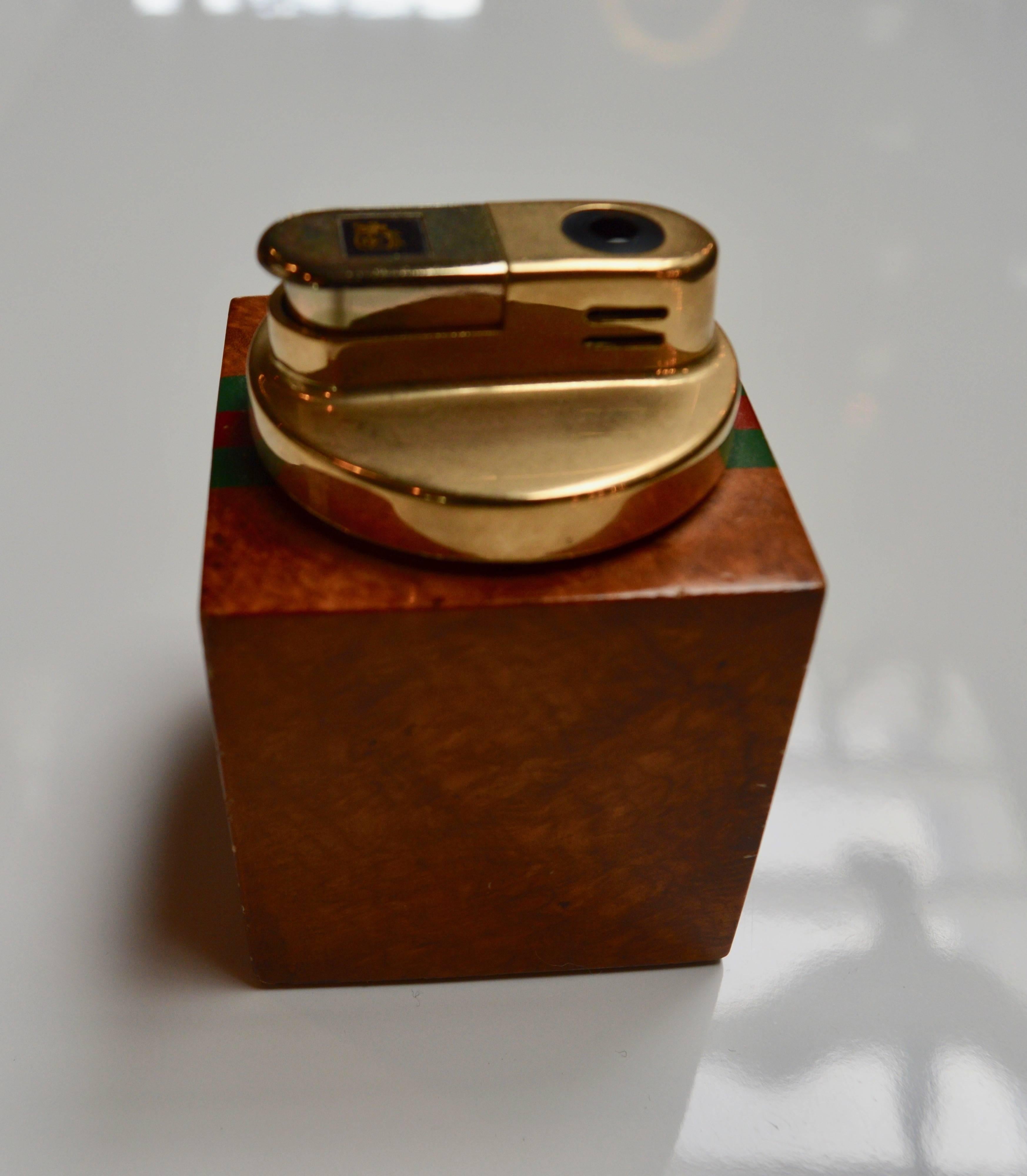 Beautiful matching lighter and ashtray set by Gucci. Large heavy burl wood frame with faceted inset glass ashtray. Signature Gucci stripes on both sides as well as signature GG patterned logo underneath. Lighter is Burl wood with Gucci stripes on