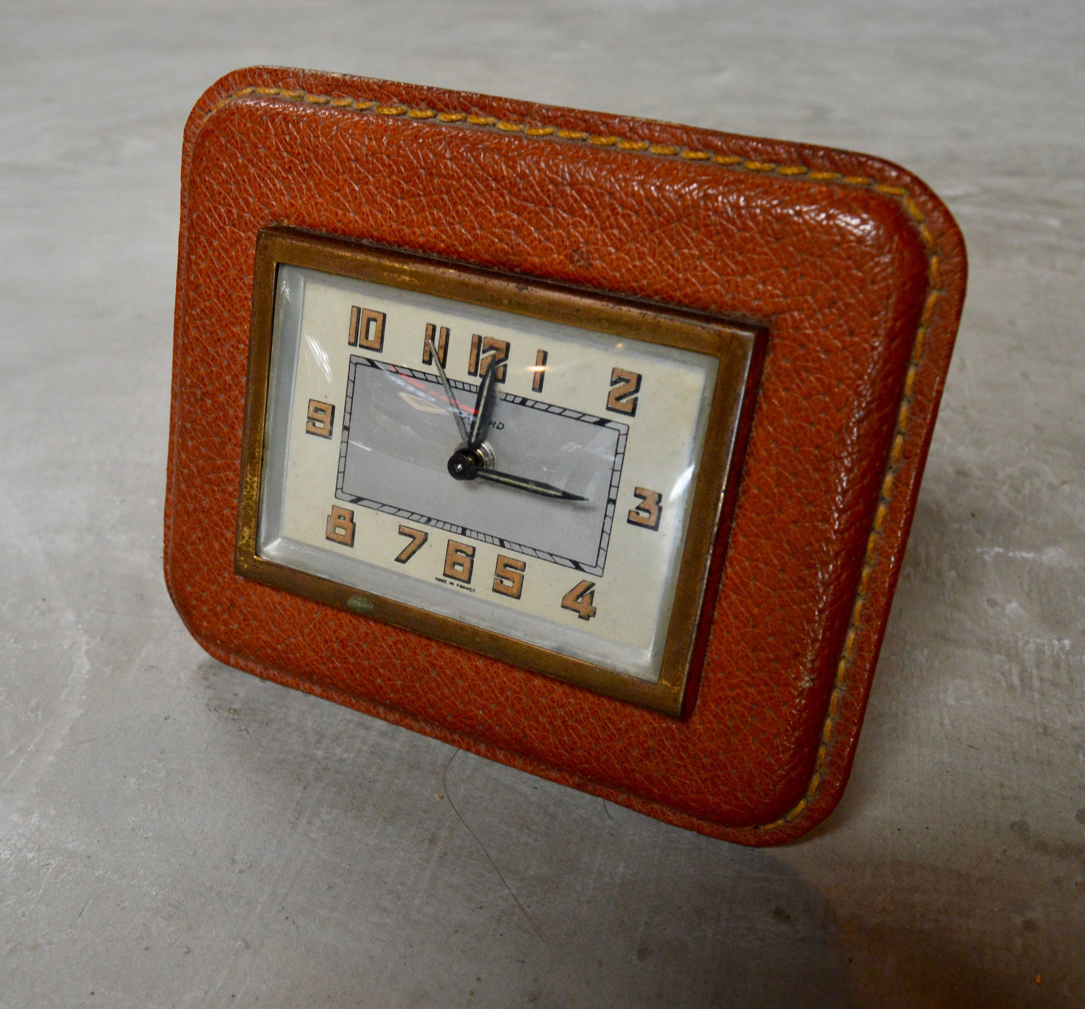 Handsome French saddle leather desk clock by Bayard in the style of Adnet. Excellent vintage condition. Keeps good time. Great patina to brass and leather.