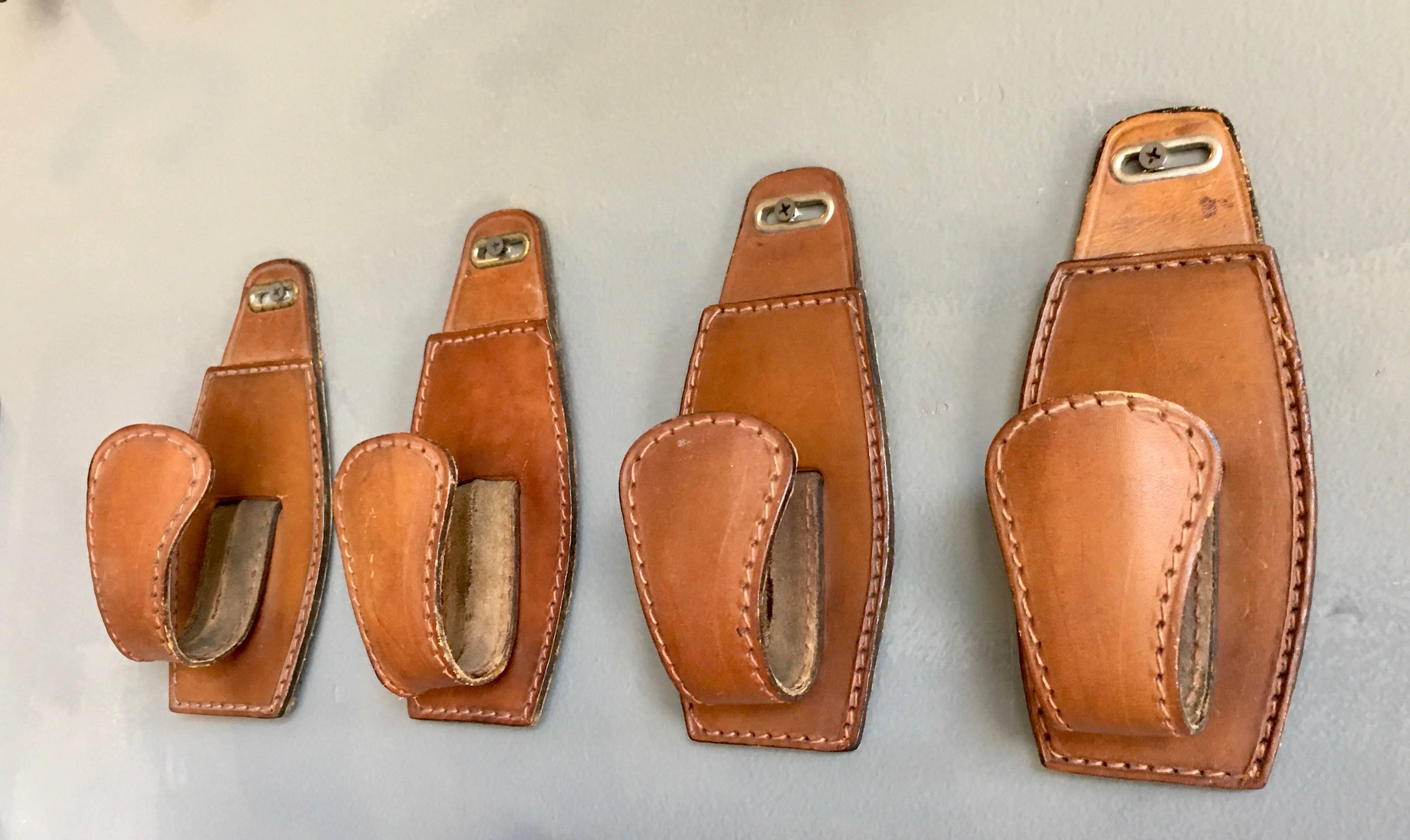 French Saddle leather hooks in the style of Jacques Adnet. Beautiful saddle leather with rich patina. Sold as a set of four. Great for hanging hats, coats and misc. Excellent condition.

Single hooks also available in separate listing.