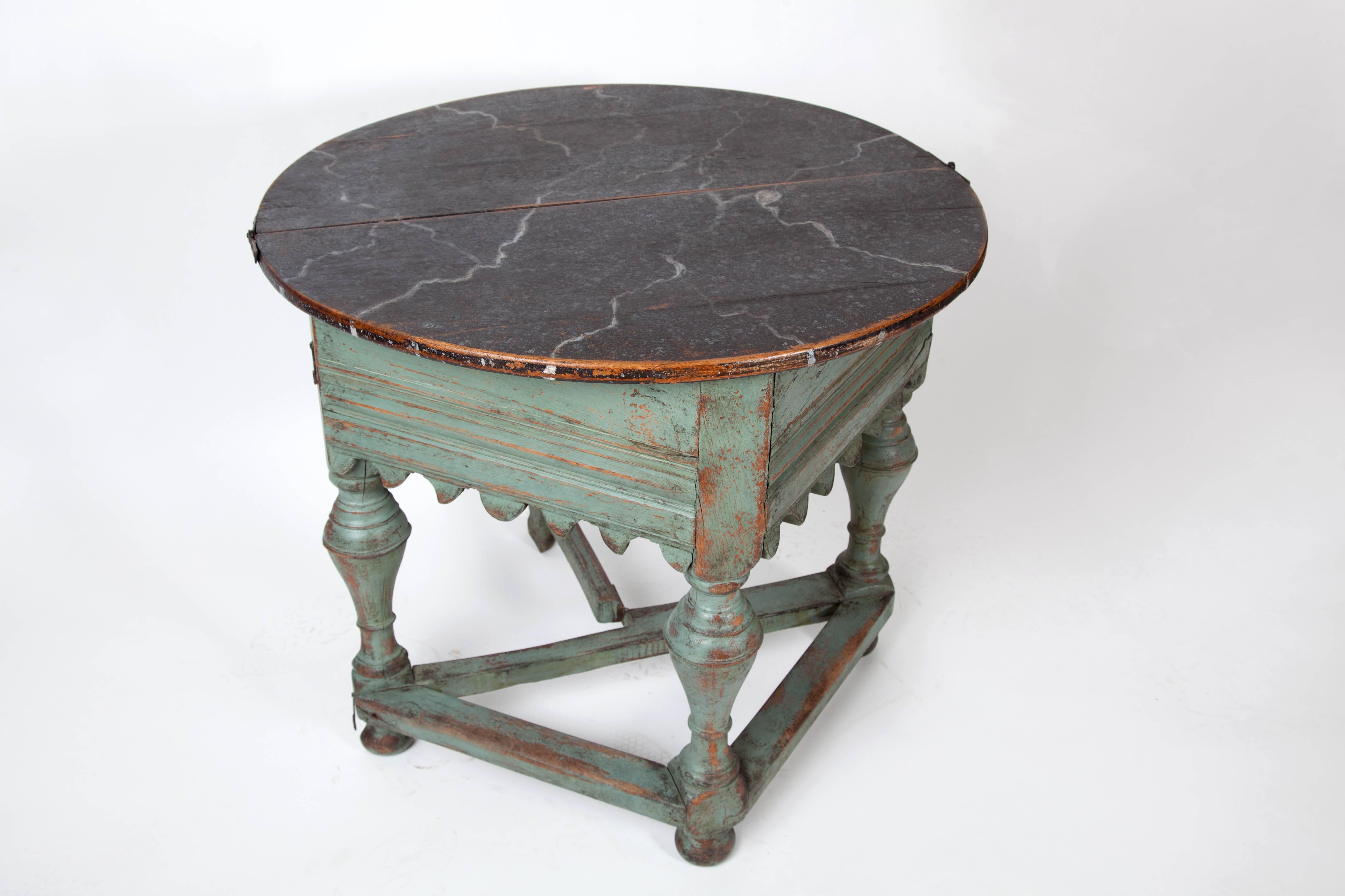 Swedish Baroque folding center table. Painted wood, in excellent condition and great character. The bottom is green; the top is faux marbled black paint. It folds into a beautiful demilune. Measures: 30.5