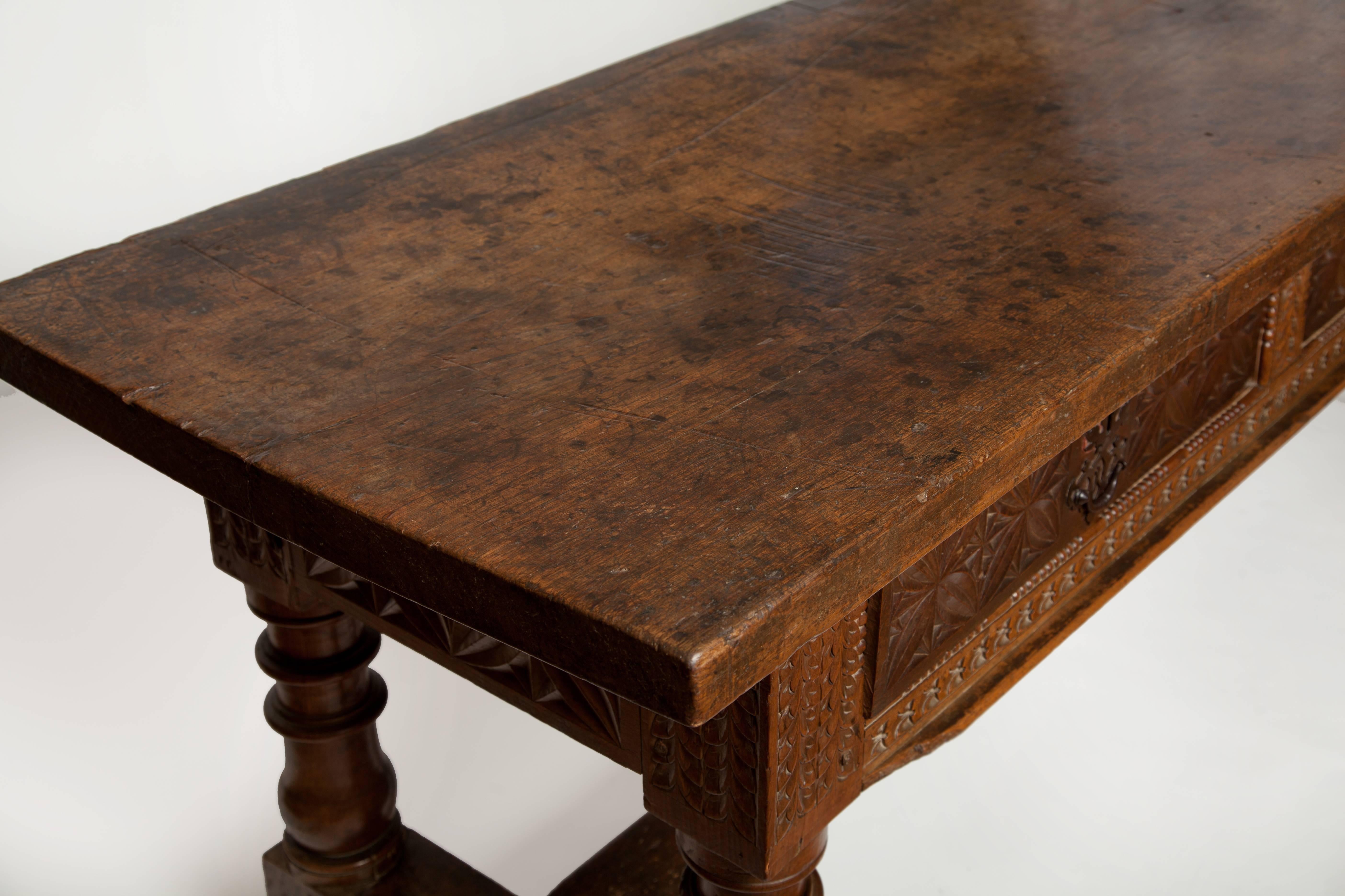 A very special antique - this is an 18th century Spanish walnut library table with single plank top and three carved drawers. It is also fully carved on the back side.