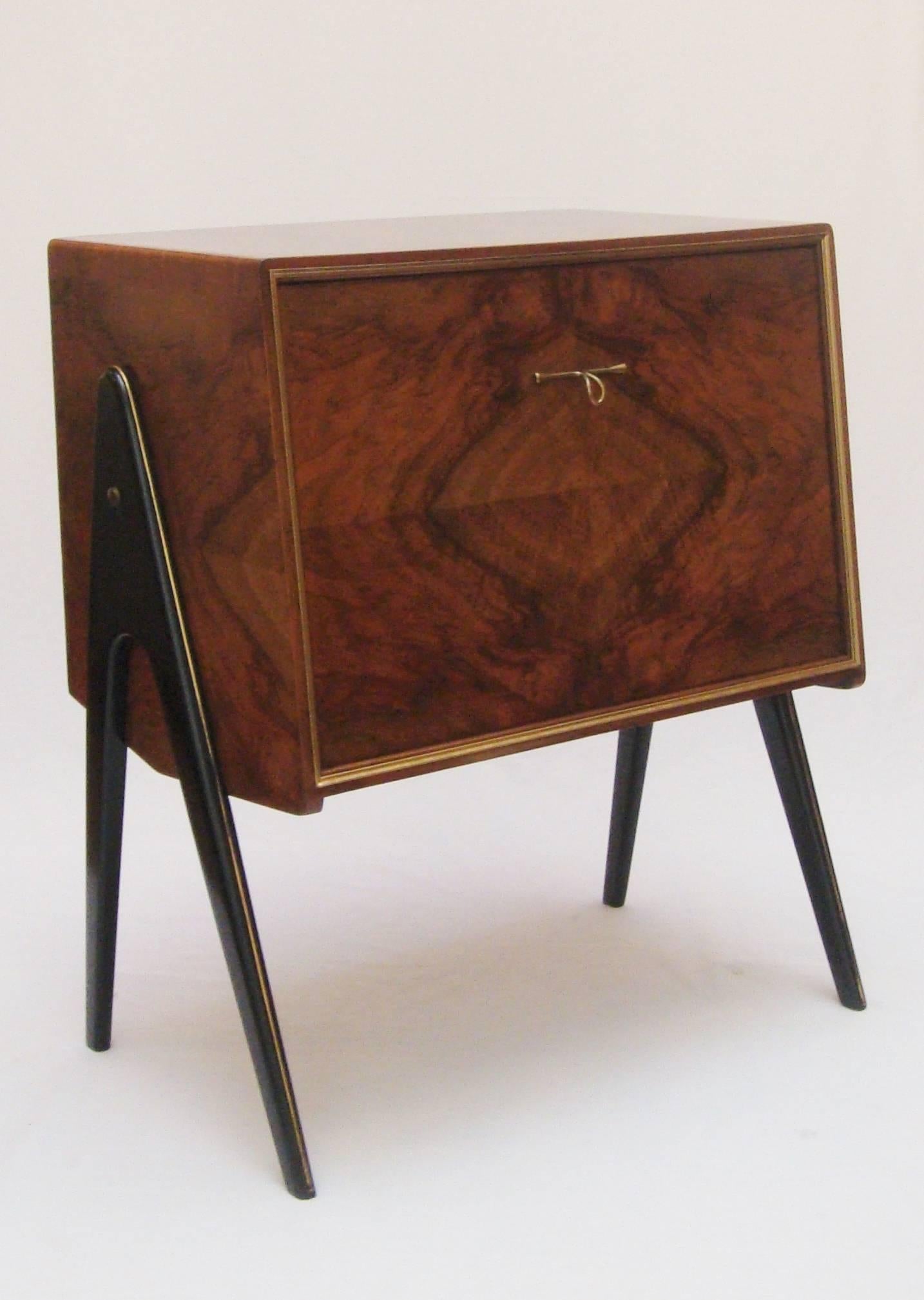 A small walnut drop front cocktail cabinet with brass trim and mirrored interior.