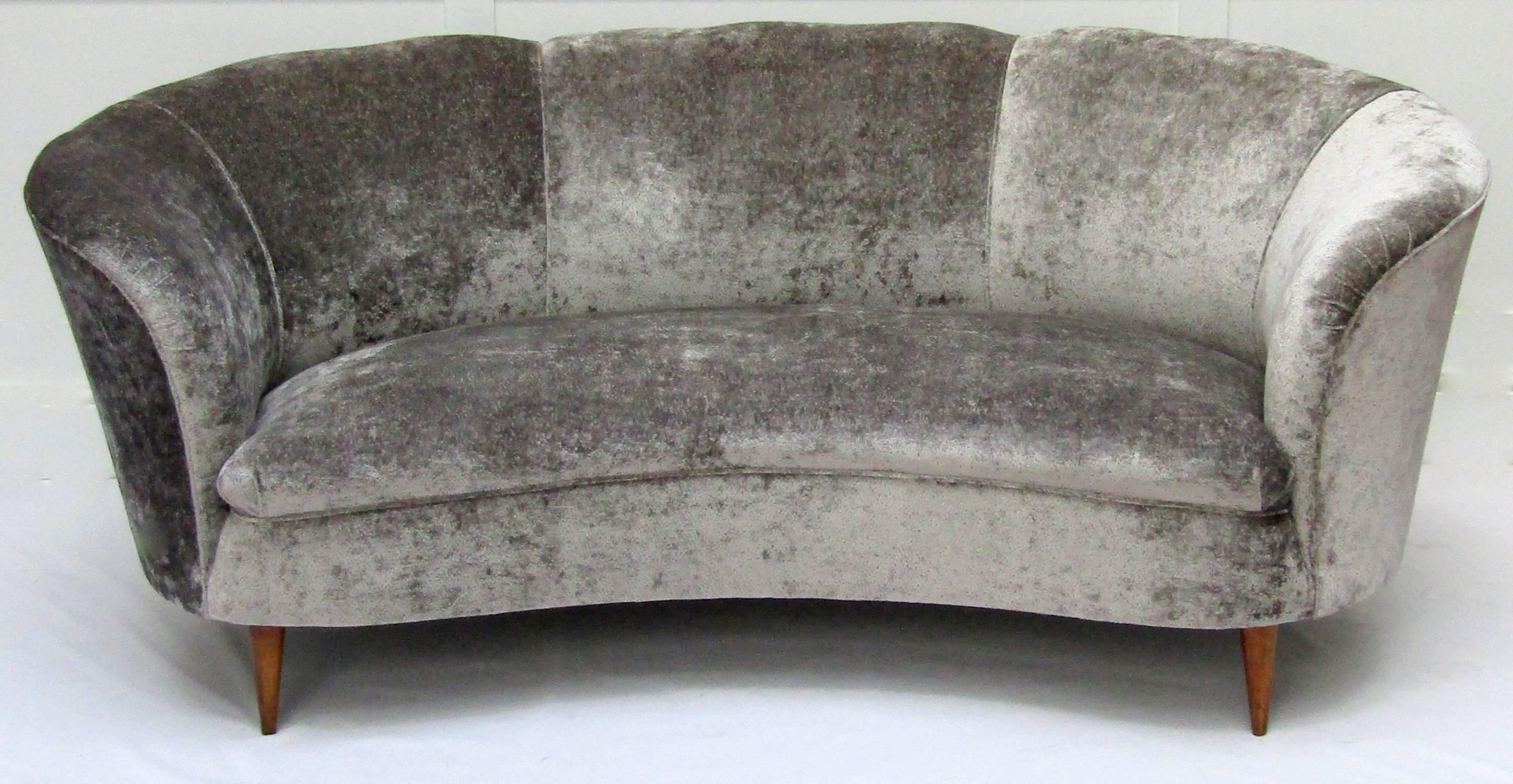 A curved two-seat sofa upholstered in
Osborne & Little Ondine velvet.
  
