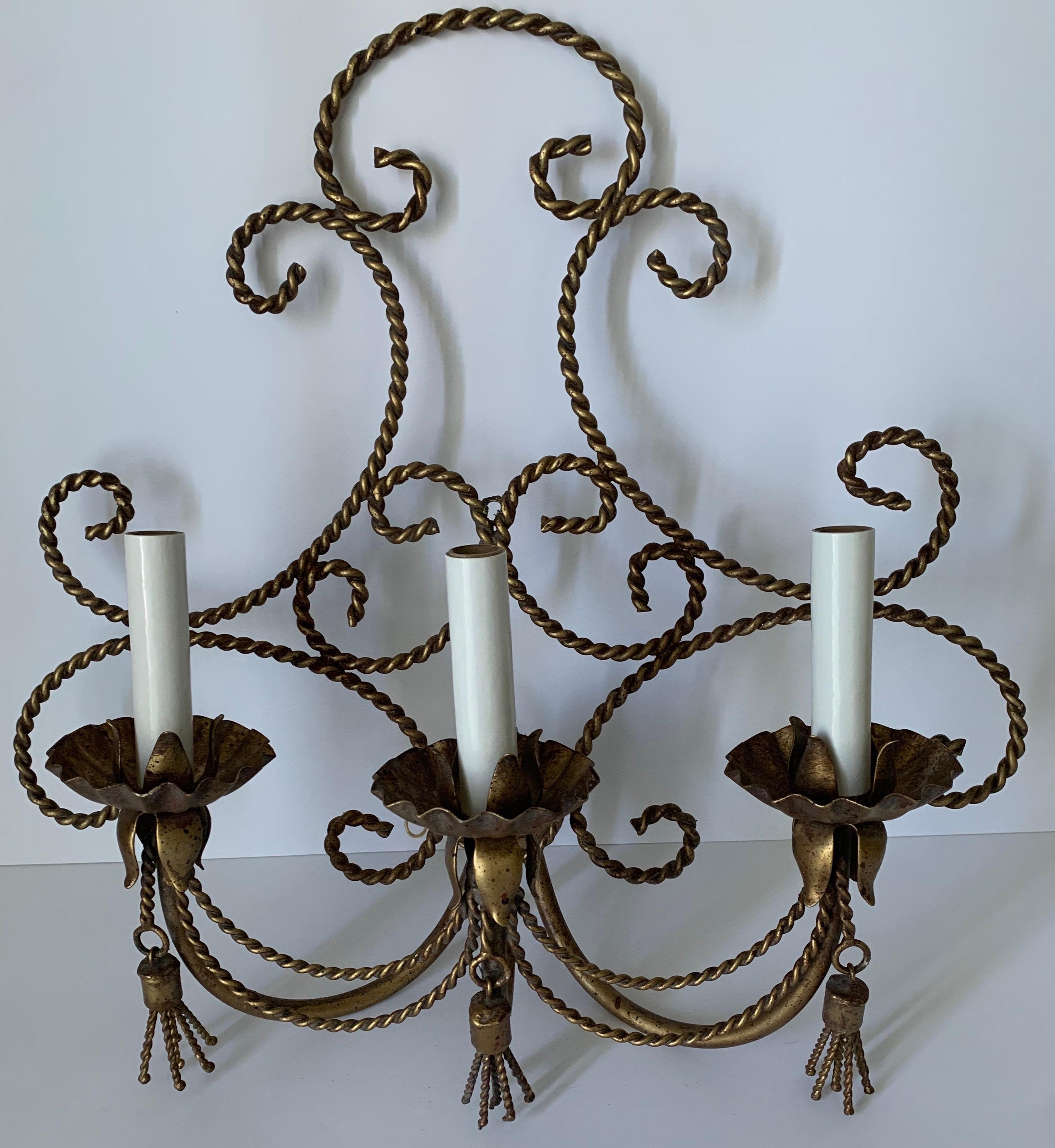 Pair of Hollywood Regency Italian gilt rope and tassel scones. Gilt painted metal with tassel detailing and flower center medallion. Newly rewired. Each light takes three chandelier bulbs (not included).

Please note that additional components such
