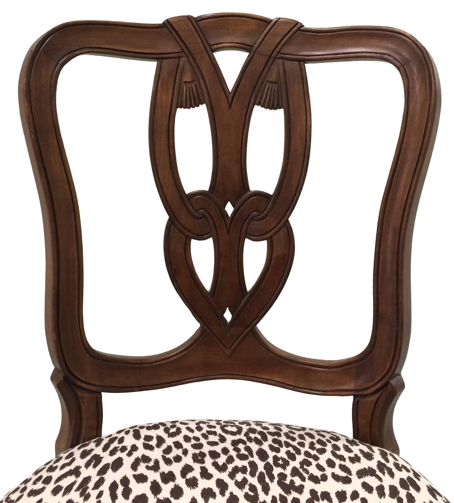 Pair of Hollywood Regency style chairs by Kindel Furniture. As found brown stained finish with carved tassel detailing. Newly upholstered in Raoul Textiles 'Leopard' linen in brown and cream. Measures: Seat 18