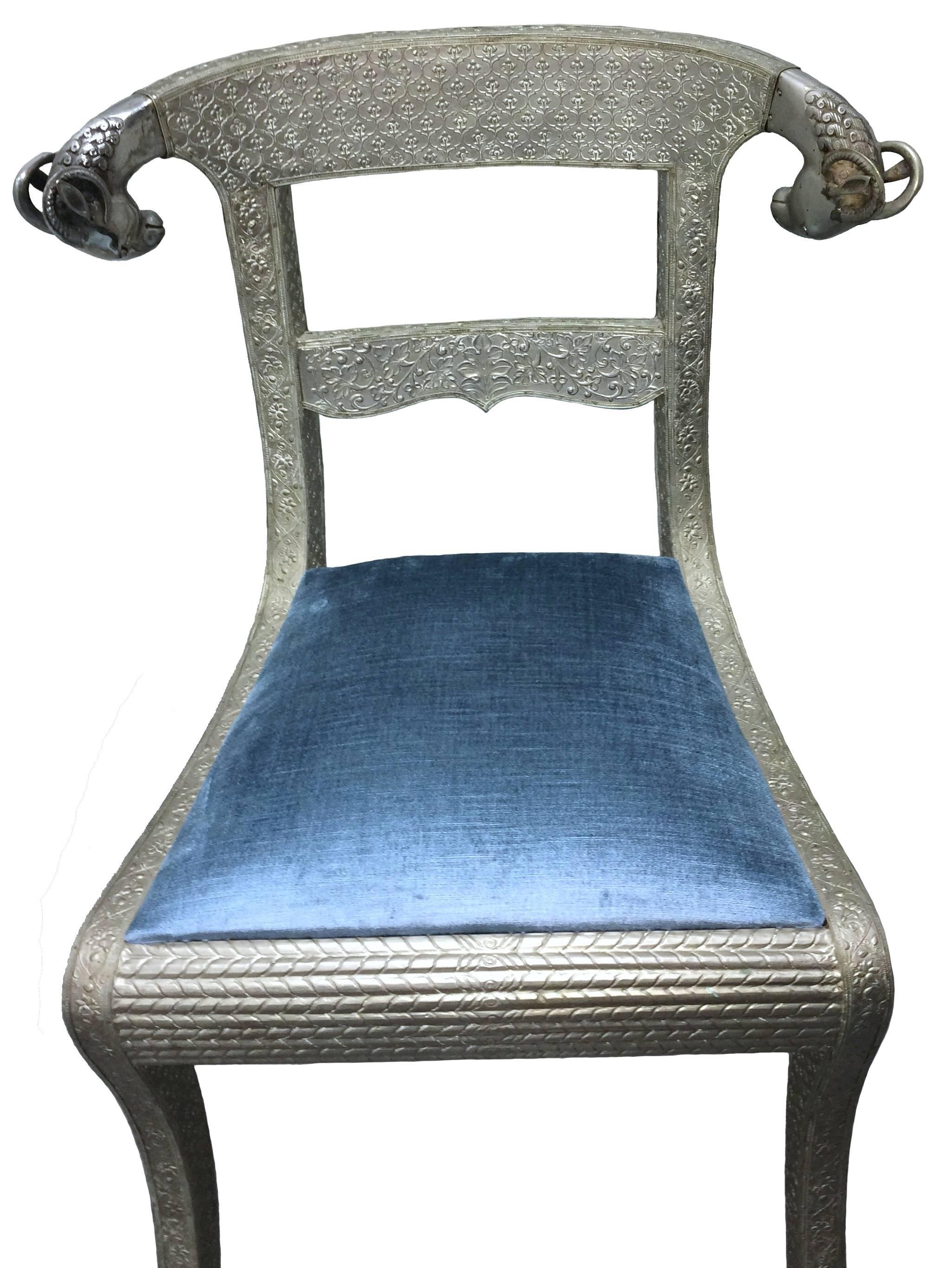 Mid-Century Indian side chair. Repoussé silver tin over wood with detailed ram's head finals. Curved back rail design. Upholstered in blue silk/velvet fabric. Seat, 18