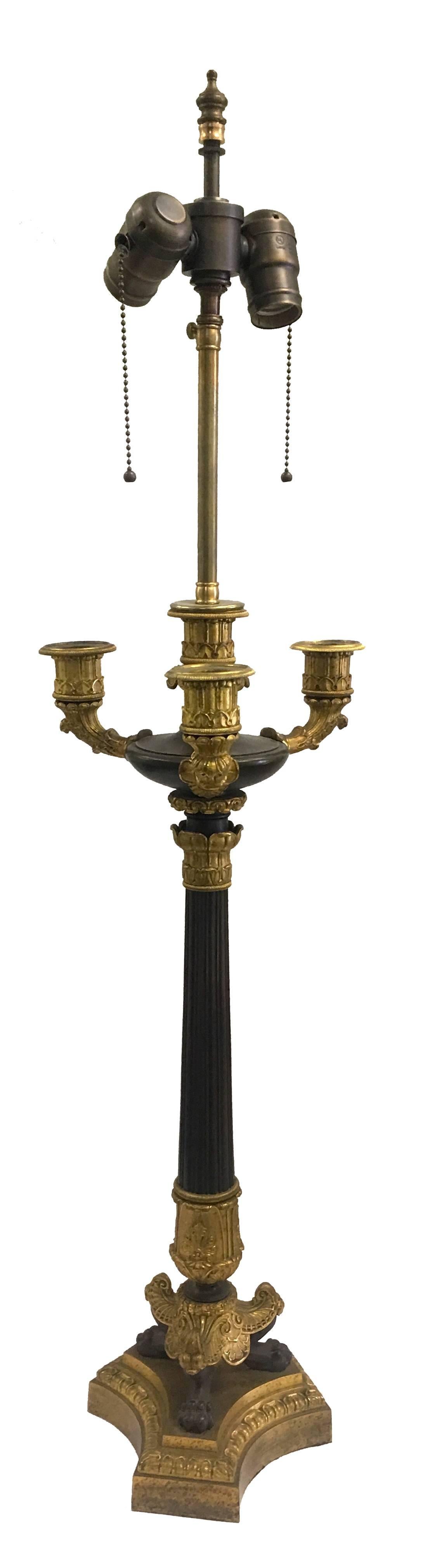 19th century French Empire ormolu and patinated bronze converted candelabra lamps. Center reeded column stem on a tripartite base on lion paw feet.
Newly rewired with new double sockets. Each lamp takes two standard bulbs. Custom cream linen