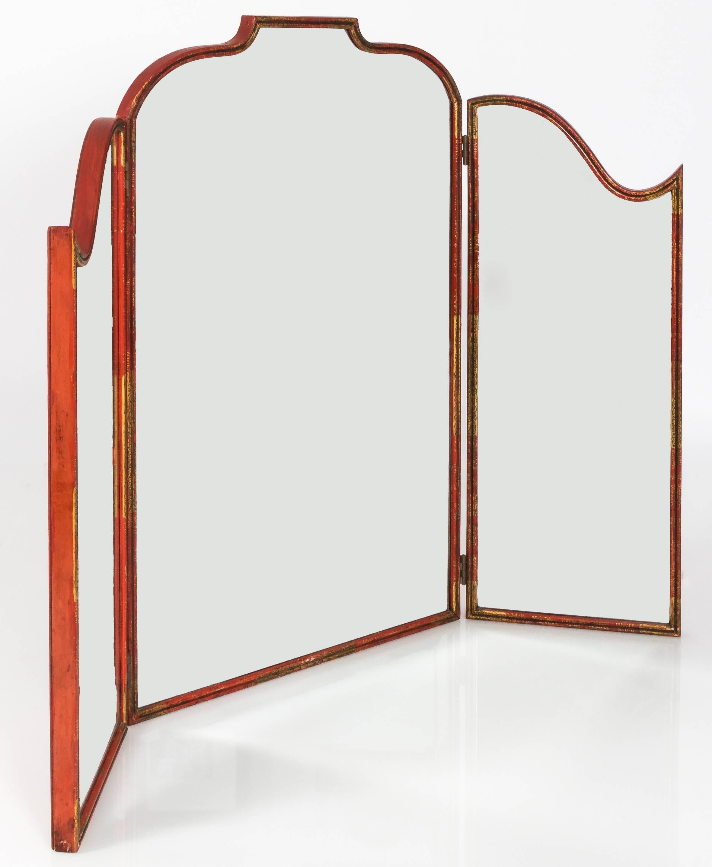 Cinnabar red chinoiserie tri-fold vanity mirror with all-over hand-painted gold detailing. Original beveled mirrored inset glass. Back is painted in cinnabar red lacquer.