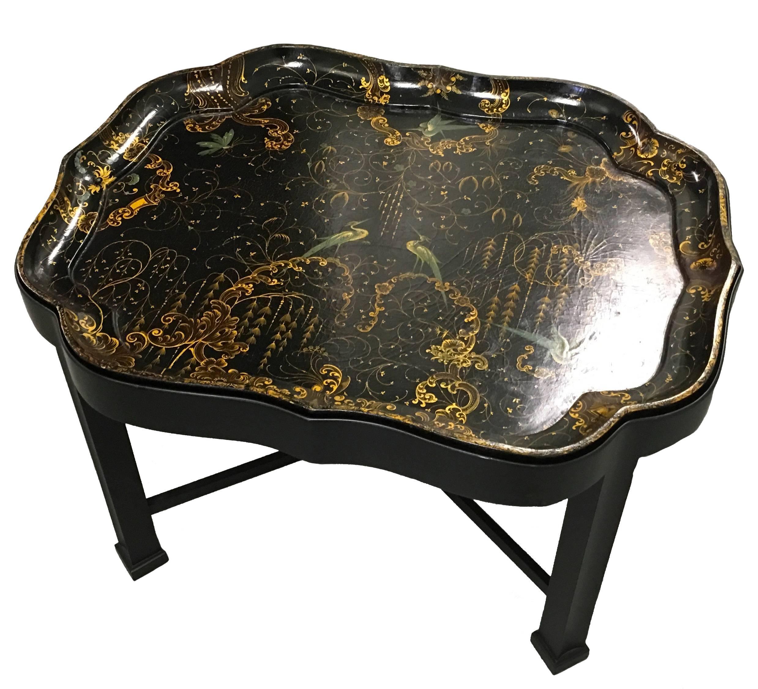 English Regency papier mâché tray table in the style of Henry Clay. Peacock motif polychrome scene with gilt detailing. Custom stand of a later period in black lacquered wood.
