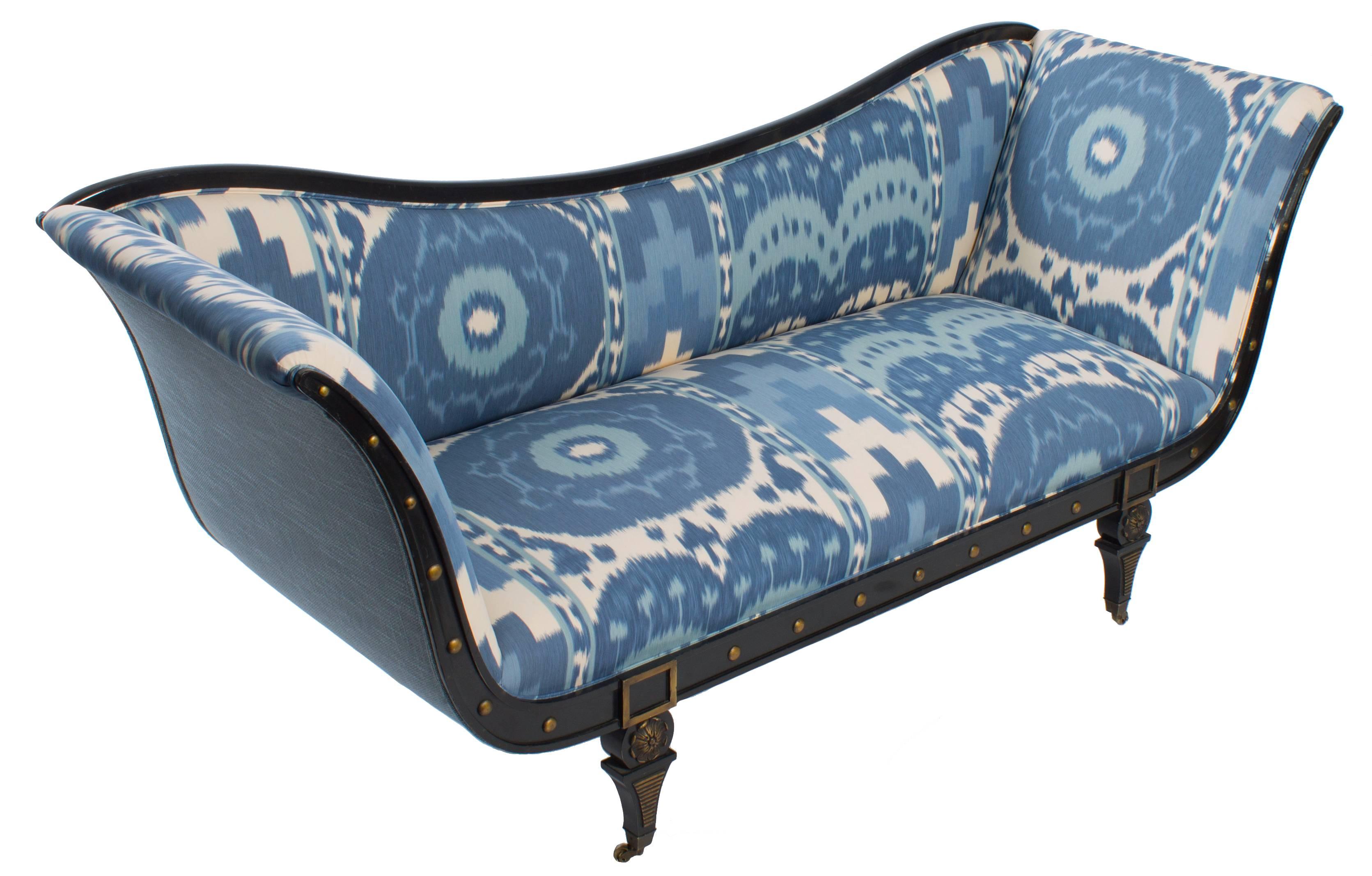 1940s Hollywood Regency style sofa. Original ebonized lacquer finish with giltwood and brass detailing. Original brass castors. Newly upholstered in Schumacher Samarkand Ikat fabric in blue. Backed in French blue basketweave linen.