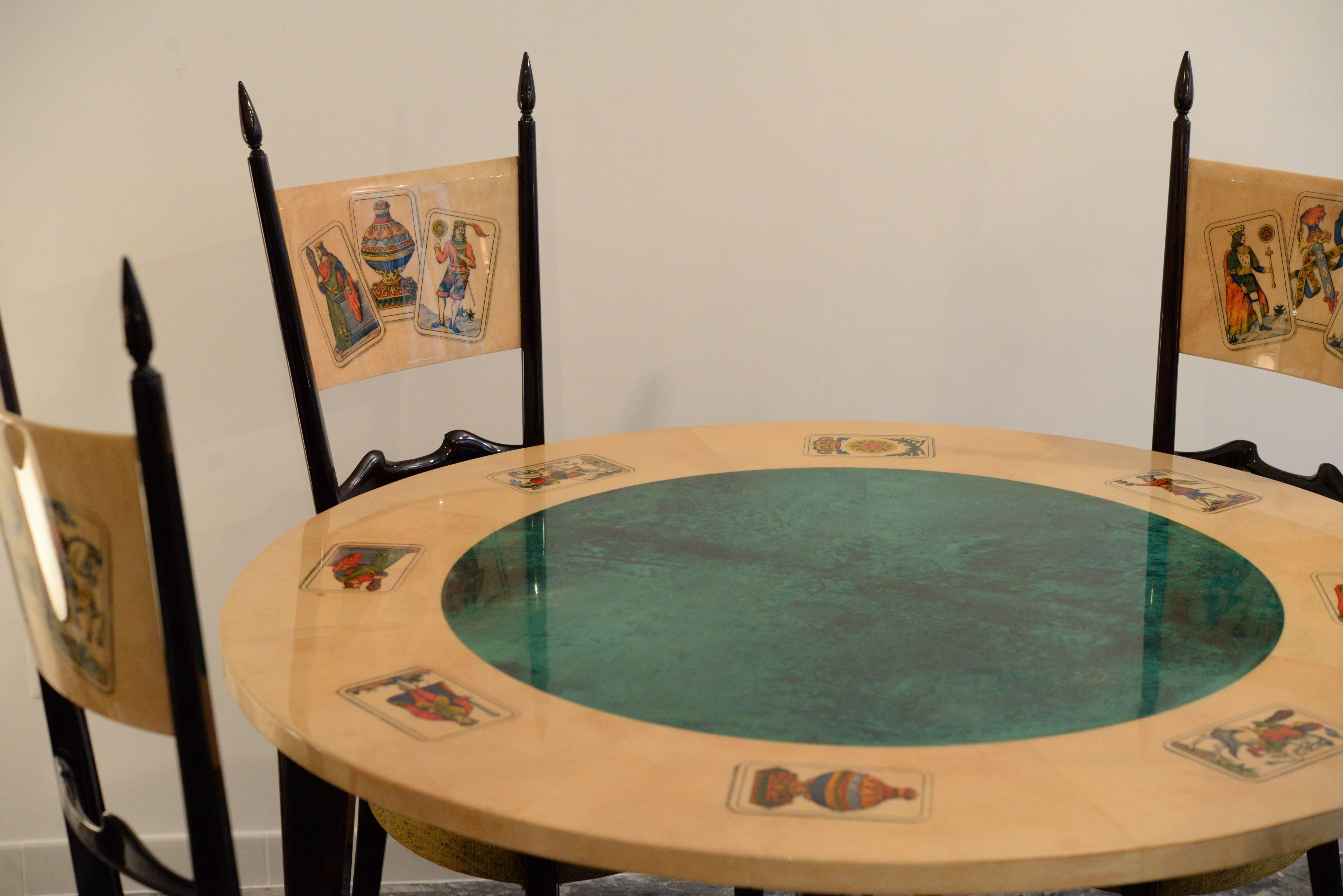 Set of four chairs and dining table depicting playing cards. 
Exquisite 1950s high back dining chairs, that have a regal quality. 
The back panels of the chairs are in parchment and ebonized wood base also.
Chairs' dimension: Depth 60 cm,
width