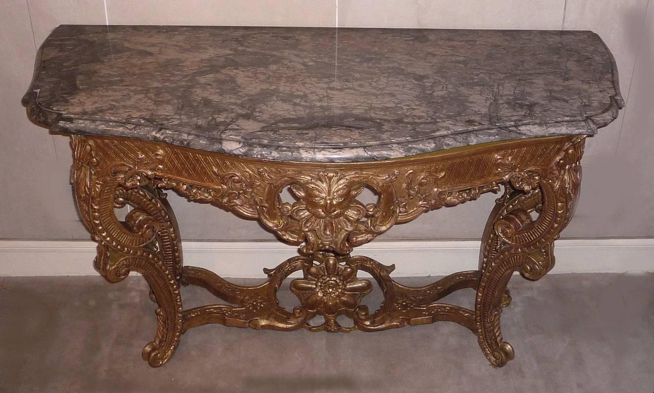A fine French Regence or early Louis XV giltwood console table, with lion’s head, circa 1730, original grey marble top.