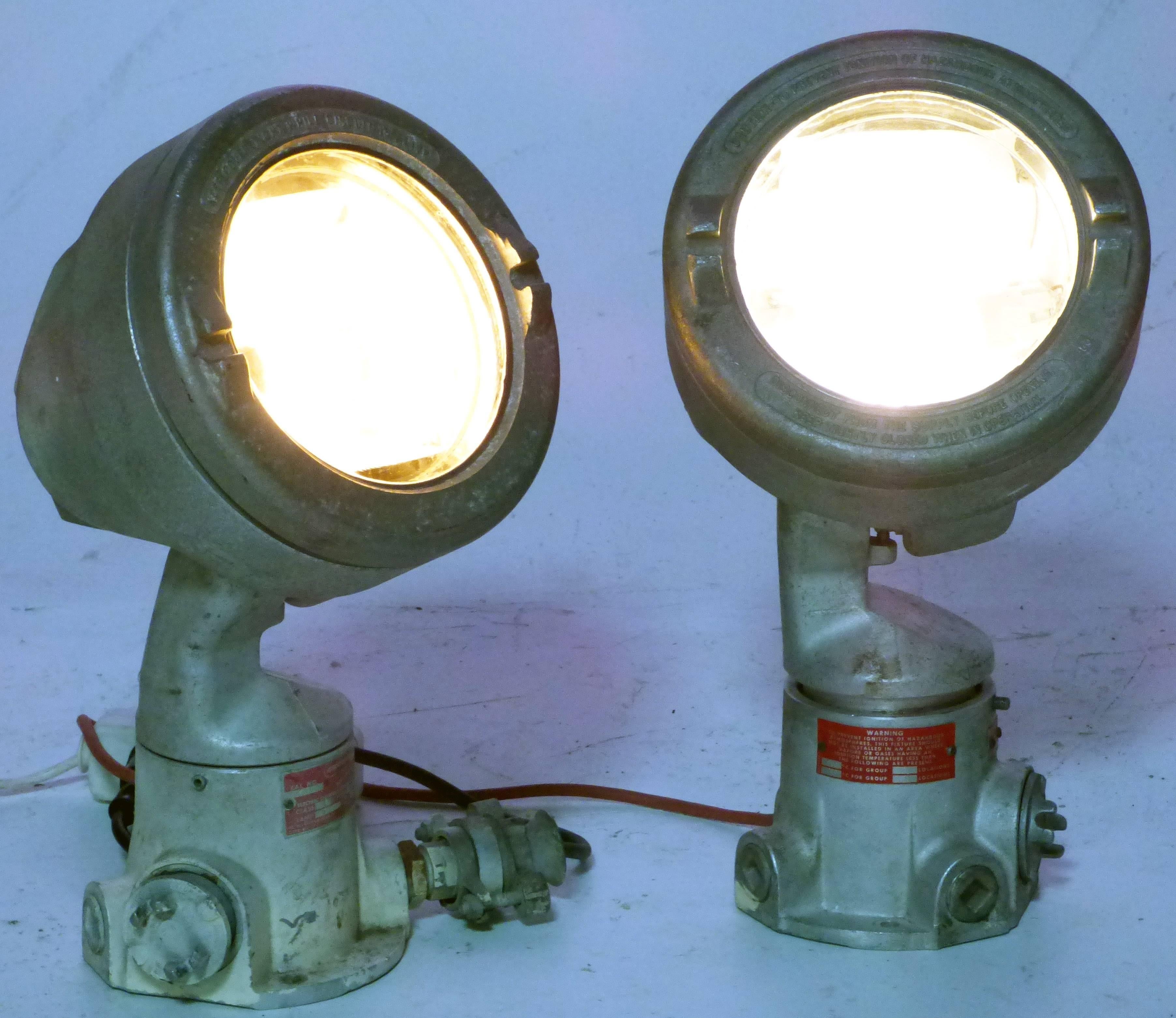 Very heavy and massive signal spotlights by Crouse Hinds for nautical use.
Both lights are made massive metal. The heads are swiveling up and down. 
So, they perfectly work as floor lamps for direct or indirect light.

Plugged with a schuko
