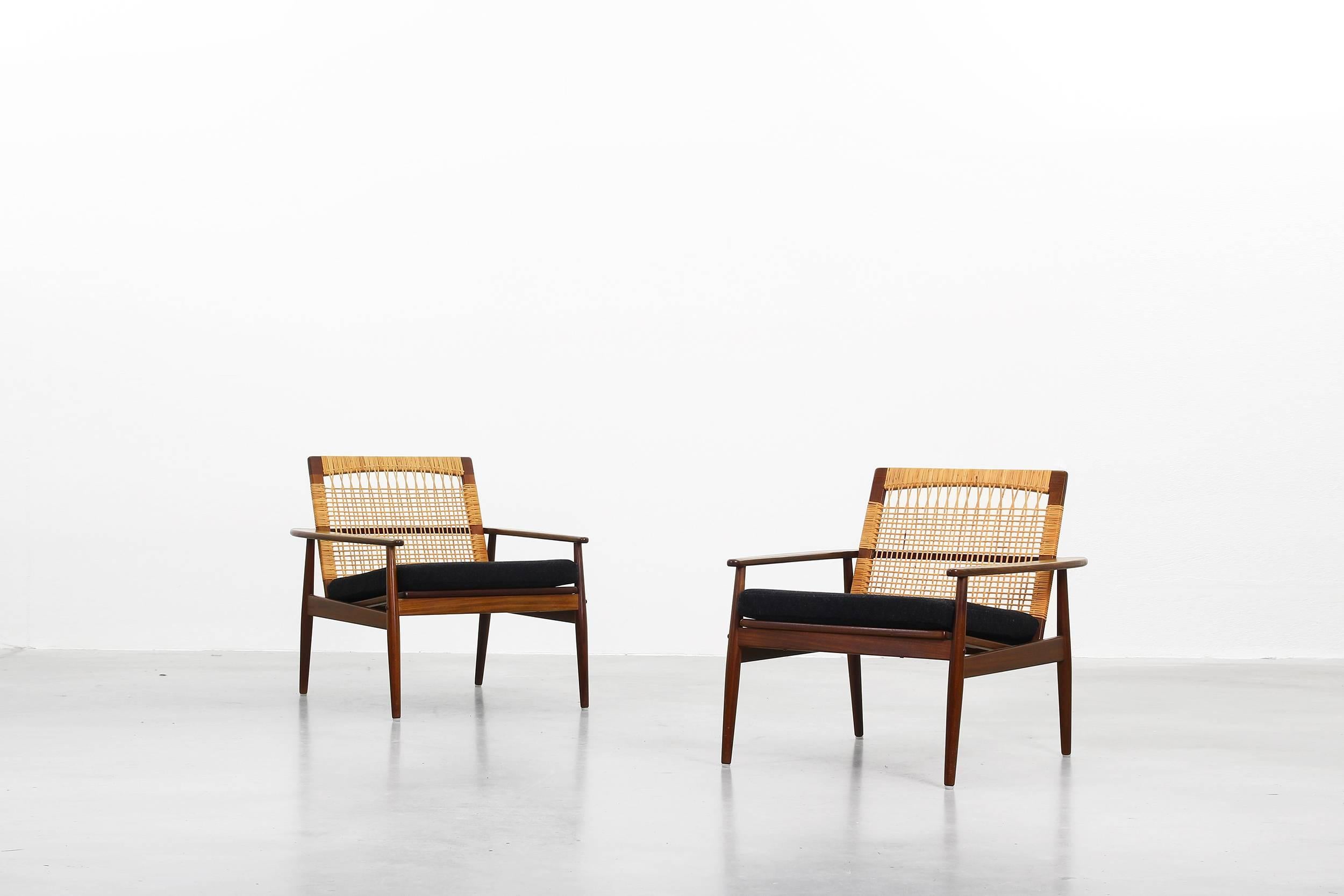 Very rare pair of lounge chairs designed by Hans Olsen for Juul Kristiansen in 1959. Both chairs are in a very good condition with just little signs of use. The frame is made of teakwood and the back comes with a mesh of cane. Further the cushions