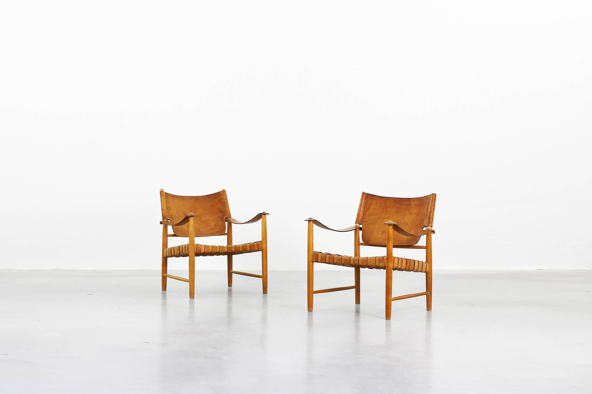 Very beautiful lounge chairs made of beech and brown leather, made in Germany in the 1950s. Both are in a very good vintage condition with traces of usage and beautifully patinated leather and beech frame. Absolutely rare and unique.