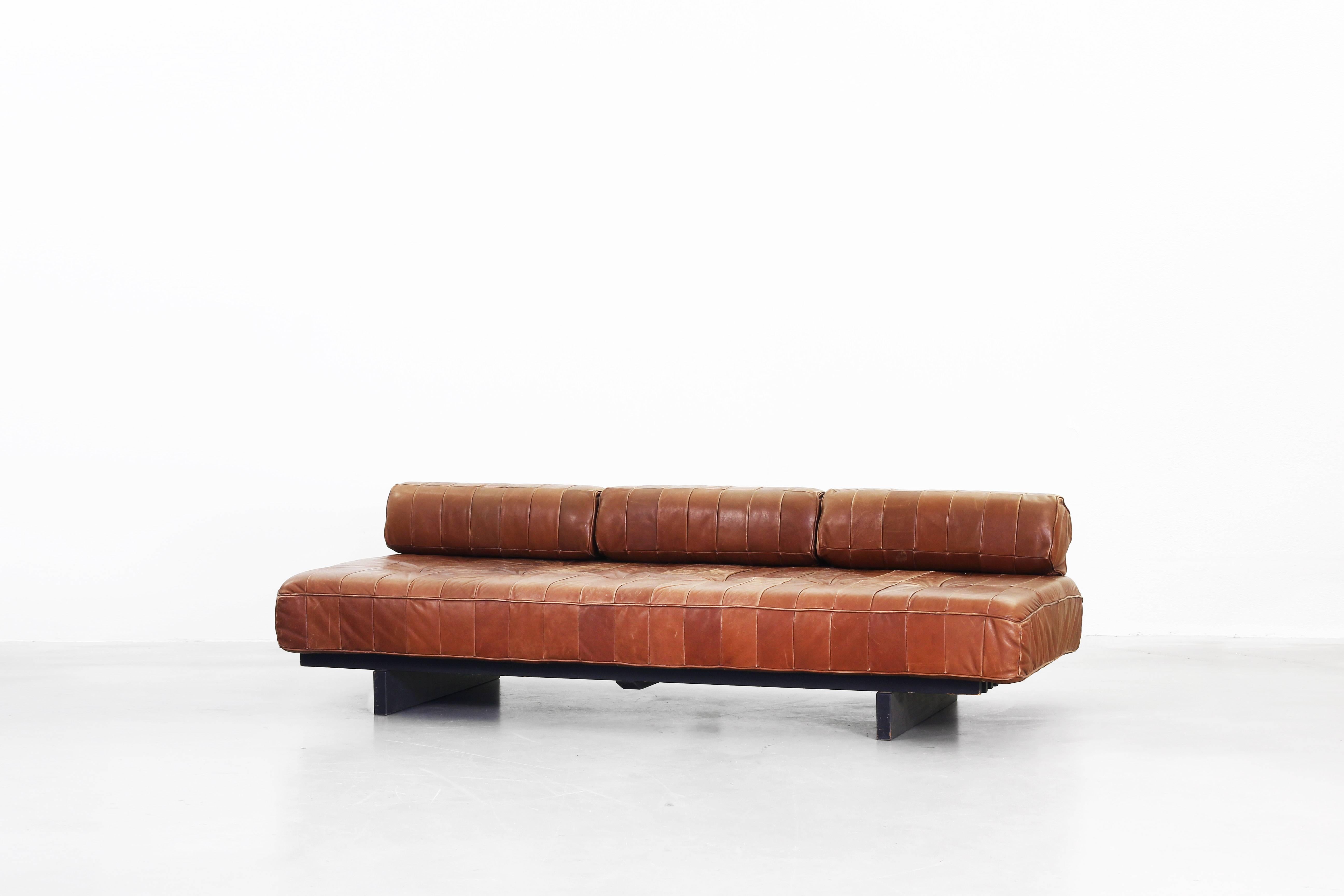 Very beautiful daybed manufactured by De Sede in Switzerland in the 1970s. The daybed comes with three cushions and a gorgeous patinated brown-cognac leather. It is in a very good original condition without any damages or repairs. We have a matching