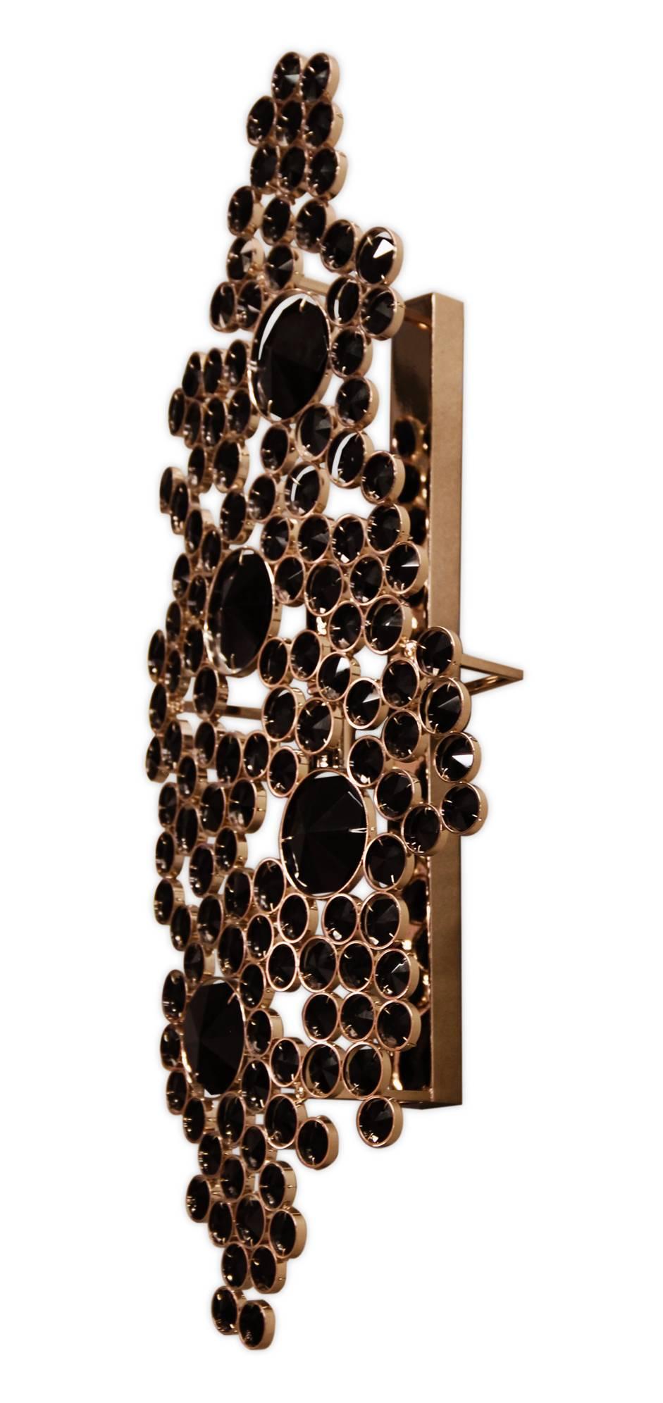 The elegant silhouette of this sconce takes its brilliance from the skillful application of the crystals. The eternal circles are individually wrapped in polished brass and placed with astonishing attention to detail. The end result is an