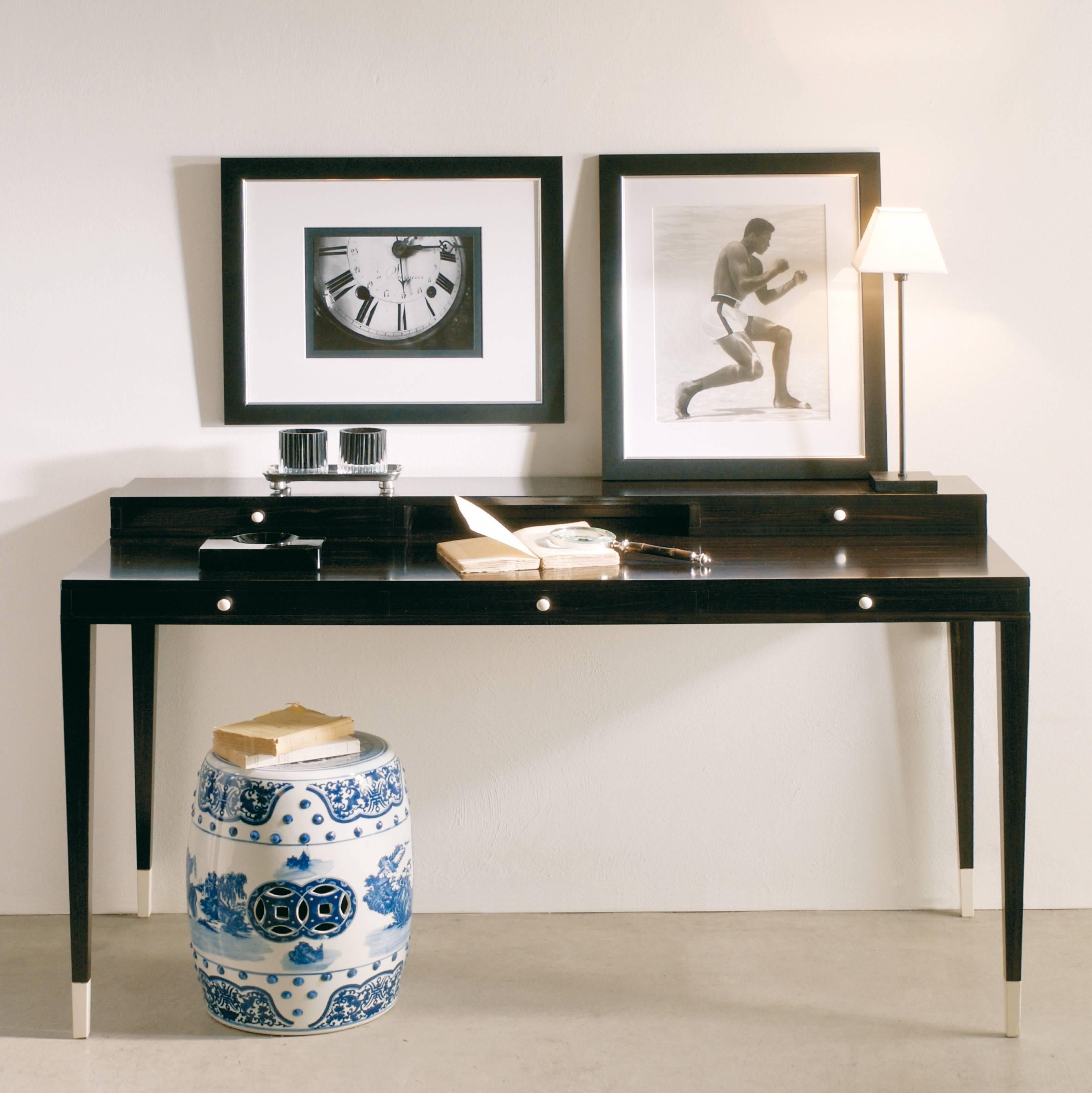 Writing desk with five drawers, available in two variants:
-Mat or gloss lacquered, with black or ivory galuchat finishing leather top and ivory coloured handles and tips.
-Macassar ebony veneered, in mat, semi-gloss or gloss finish, with ivory
