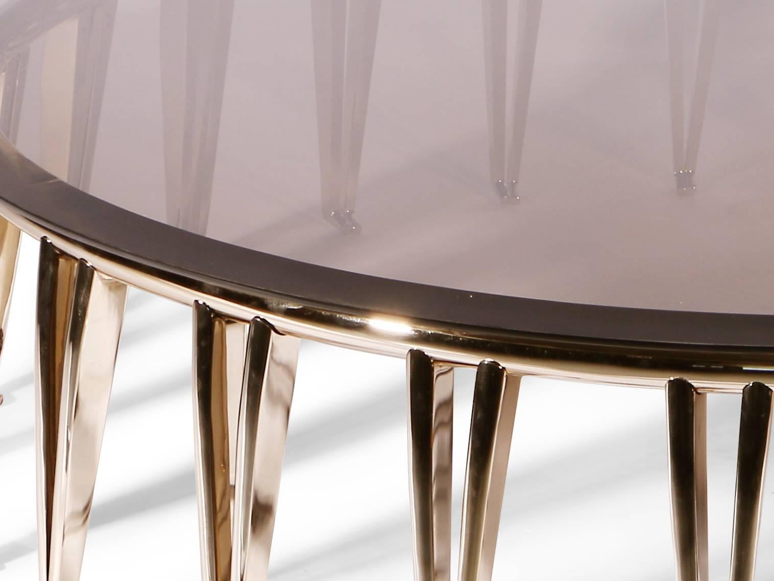 The Newson center table is a simple yet elegant piece. It sets up a strong contrast between the hefty brass structure with v shaped legs and the clean smoked glass surface embraced by the ring top. With it's subtle colour scheme and simple lines, it