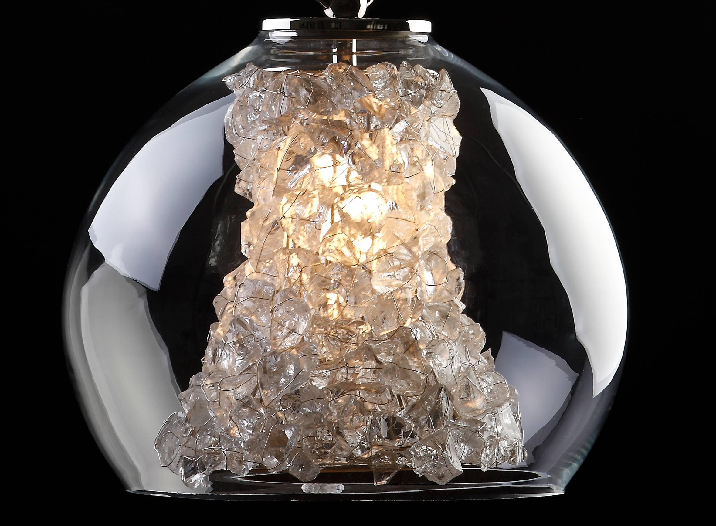 Elegant glowing glass to emulate crystals inside a round glass pendant.

Measures (cm):40 x 40 (with chain 80)
Lamps: one lamp E27 max. 40W
Class: class ii
Material: glass/brass
Finish: nickel
Weight: 10 kg
Packaging (cm):60 x 60 x 60.
 