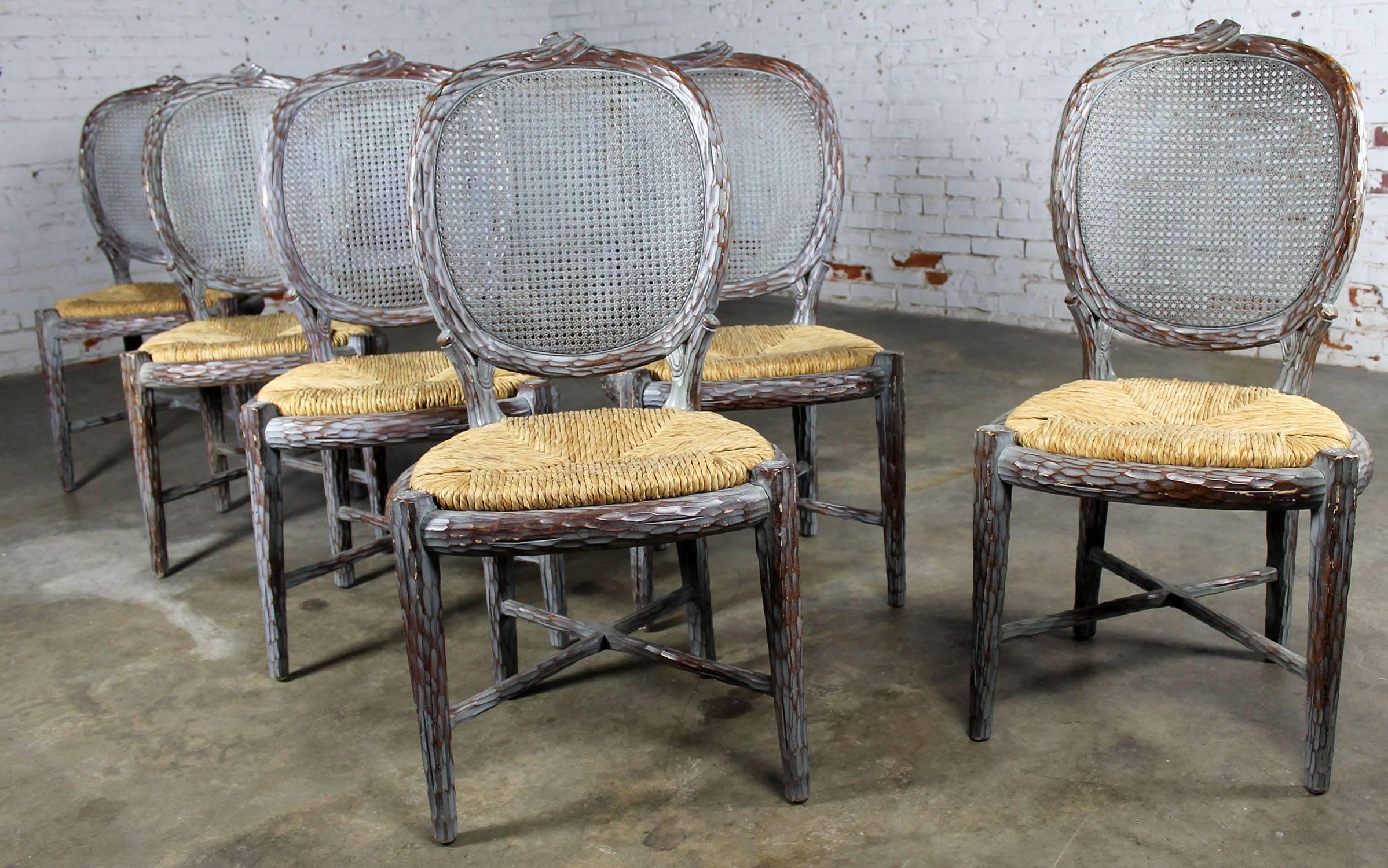 Unusual set of eight faux bois or carved twig dining chairs with caned backs and rush seats with a gray-blue washed finish. They are in wonderful vintage condition with normal wear. Maybe a few nicks here and there but nothing that doesn’t fit in