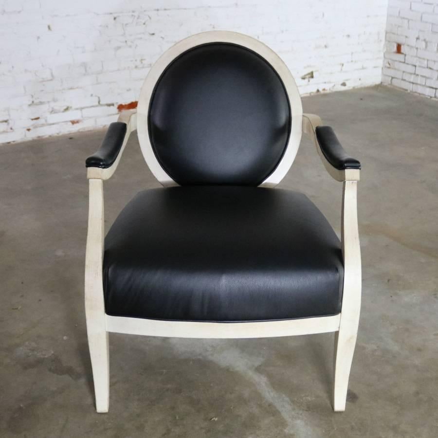 Handsome recently vintage fauteuil or open-arm side chair done in an antique white painted frame with black faux leather upholstery and transitional to contemporary styling. It is in fabulous condition and ready to use as a wonderful accent in your