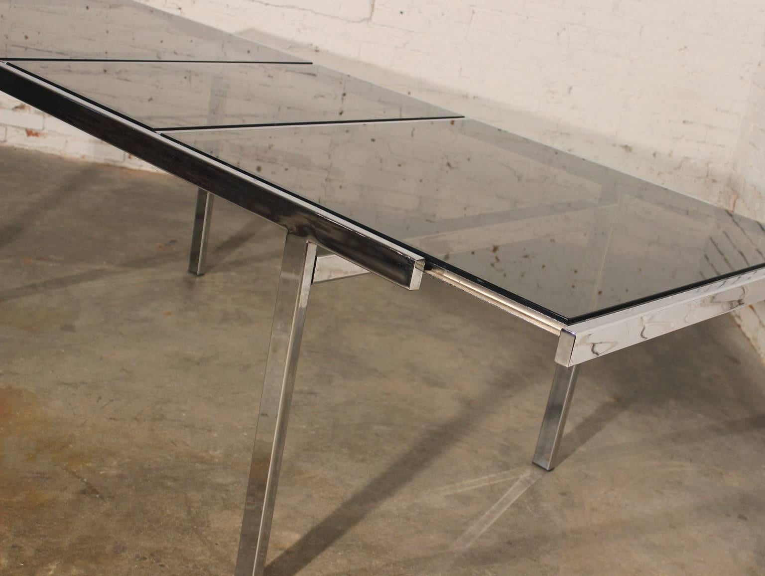Quite the innovative design in this vintage Milo Baughman expandable dining table! A kind of modern refractory table. The chrome and smoked glass is just a wonderful combination and closed this is a fabulous example of modern streamlined design.