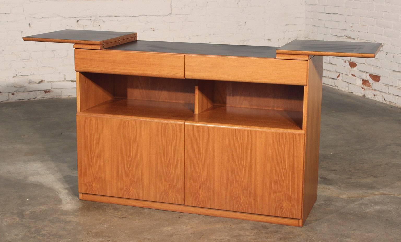 Beautiful, simple, practical and timeless vintage Danish or Scandinavian Mid-Century Modern teak dry bar with flip out wing top. This cabinet is in absolutely wonderful condition with no outstanding flaws.

This vintage Danish Mid-Century Modern