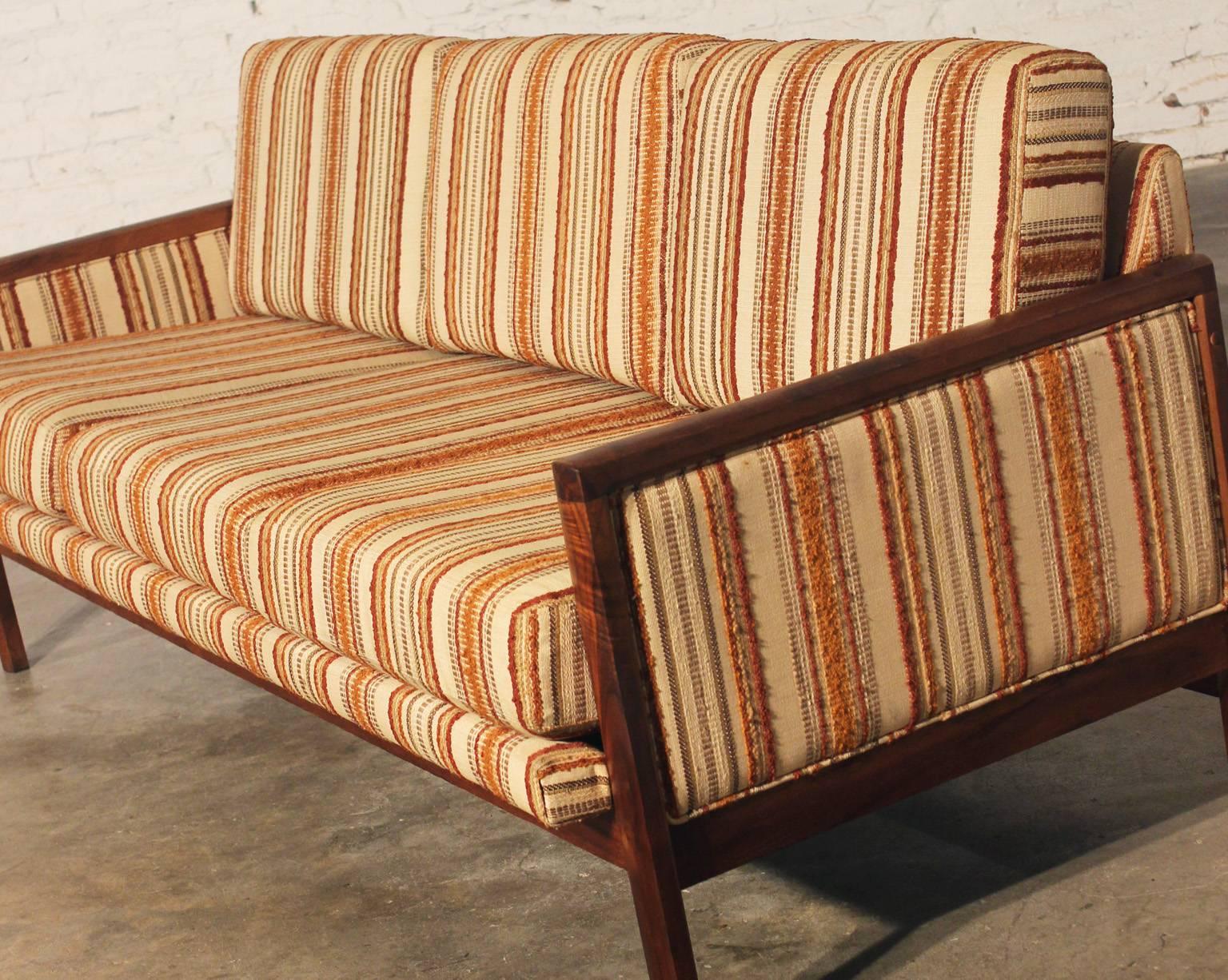 Fabulous striped Mid-Century Modern sofa with walnut trim in wonderful age appropriate condition.

This walnut trimmed sofa is a wonderful example of Mid-Century Modern simplicity. The wood trim which actually forms the legs, arms and bottom