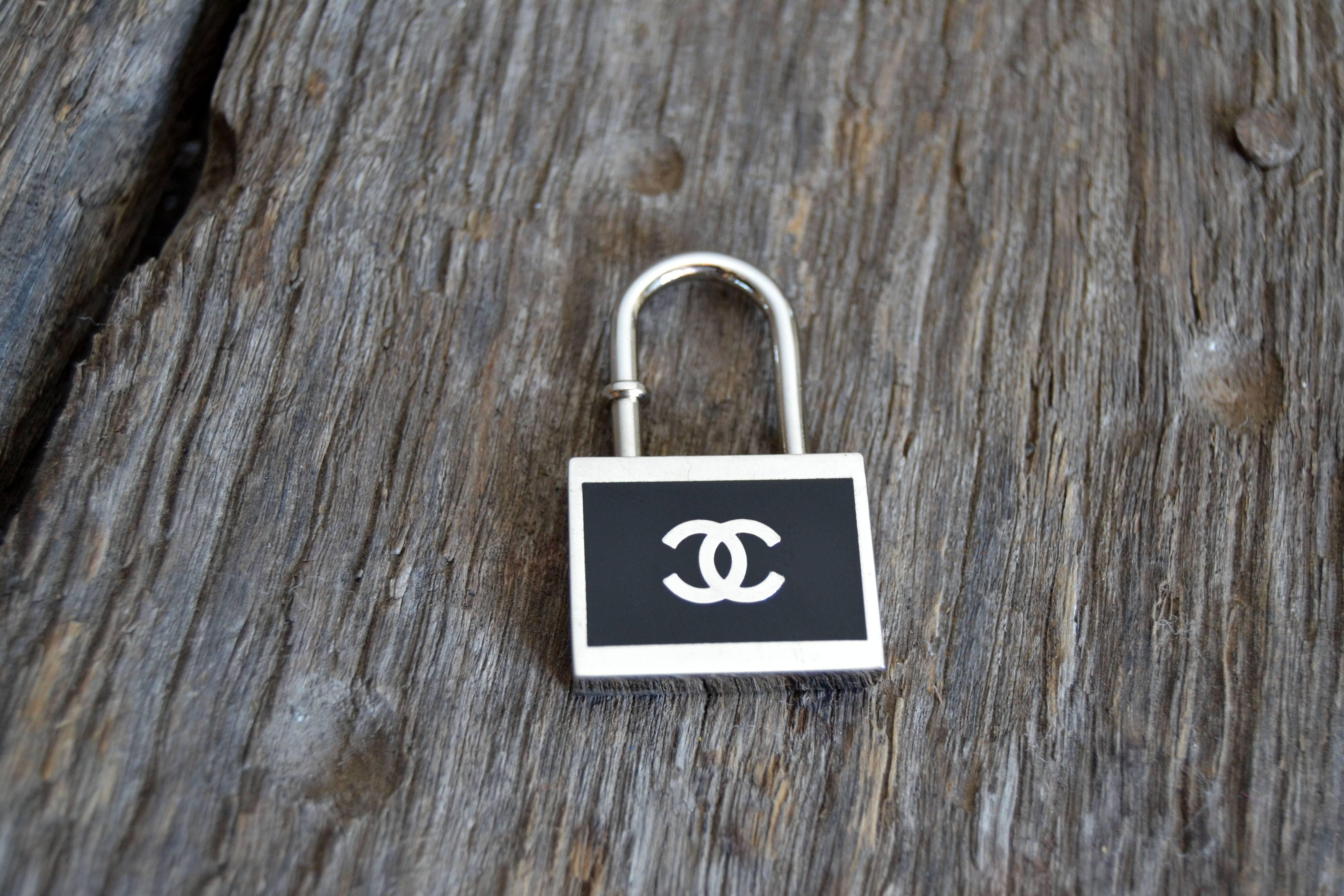 Very handsome key chain in the style of Chanel, purse charm or necklace pendant in excellent condition.

This black and silvertone padlock style key chain is very handsome and in excellent condition. At least, we are calling it a key chain;