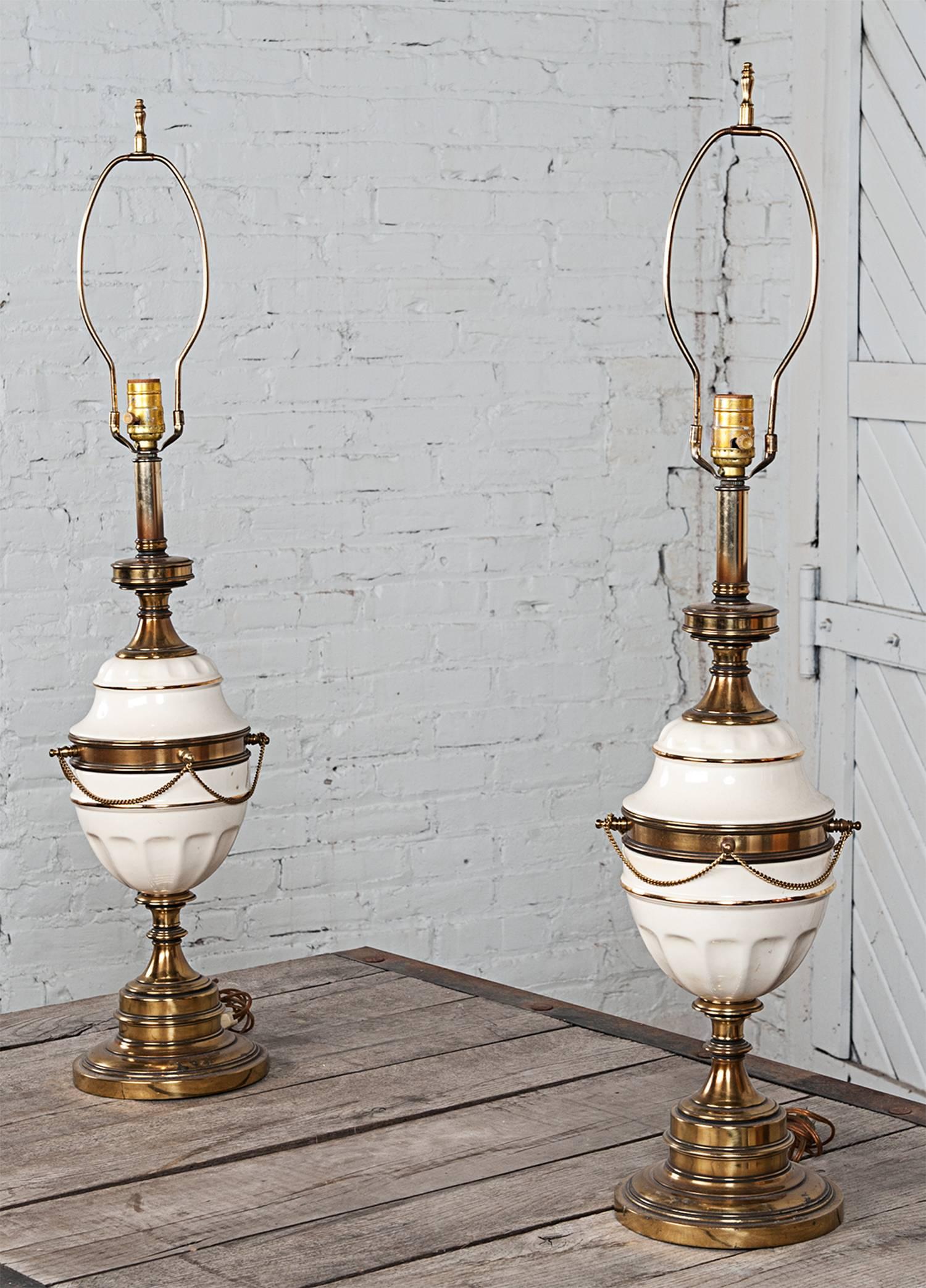 These elegant lamps are white ceramic with gold tone accents. Reminiscent of Stiffel but not marked. Sold as a pair only. Lampshades are included if you so desire and are original. All wiring has been checked and lamps are safe and functional. They