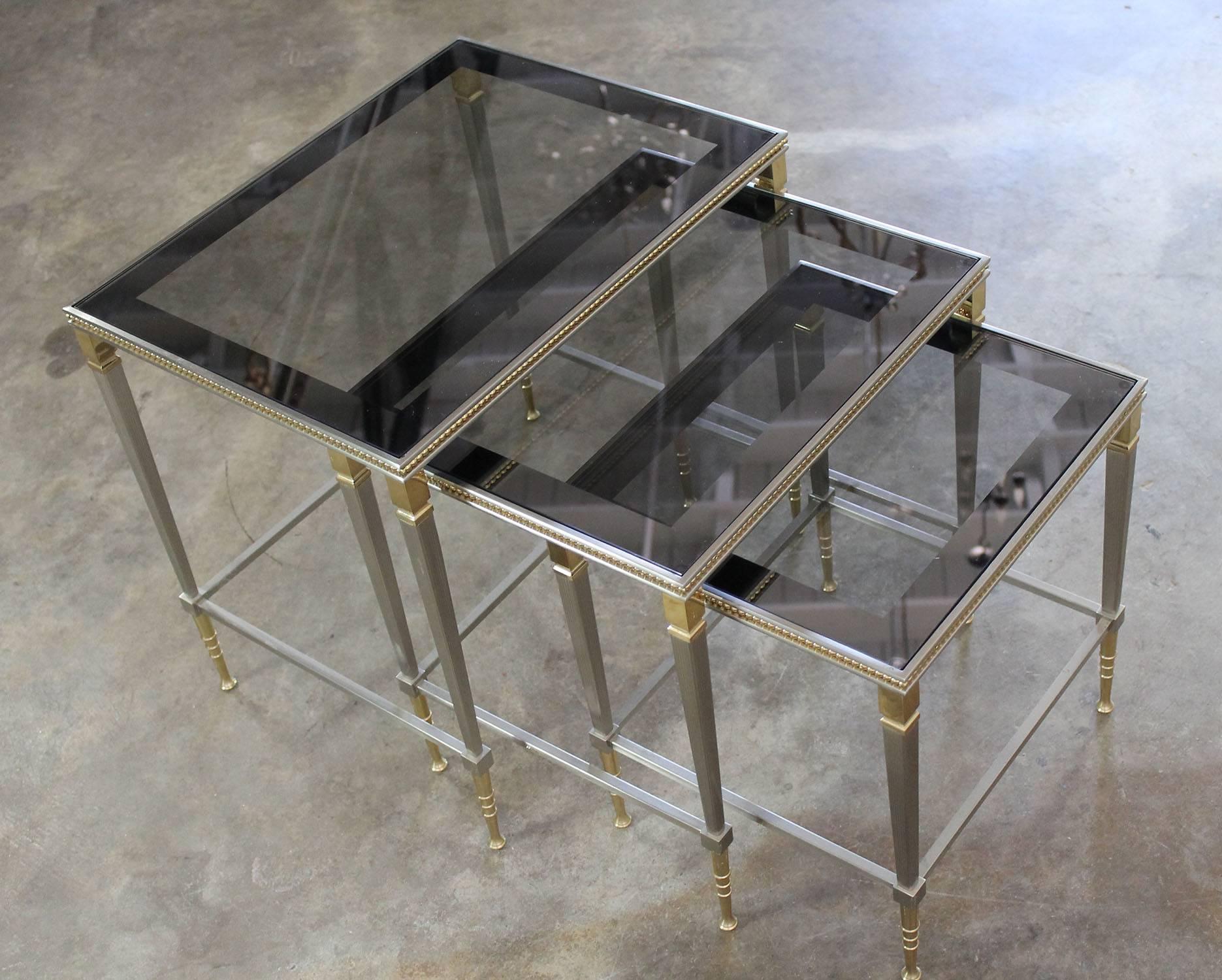 Set of three brass, bushed stainless steel and glass nesting tables. Beautiful and in great vintage condition, circa 2003.

What I know. These are gorgeous brass and stainless nesting tables with mirror edged glass tops. What I don’t know. Are