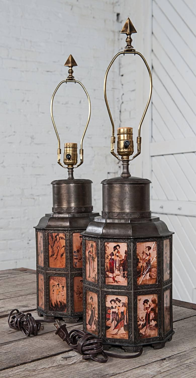 Gorgeous one-of-a-kind pewter lantern shaped Asian style pair of lamps. Each with 18 pewter framed and glass encased individual figural scenes. They are in great condition with the exception of three cracked panes of glass.

These nonagon or