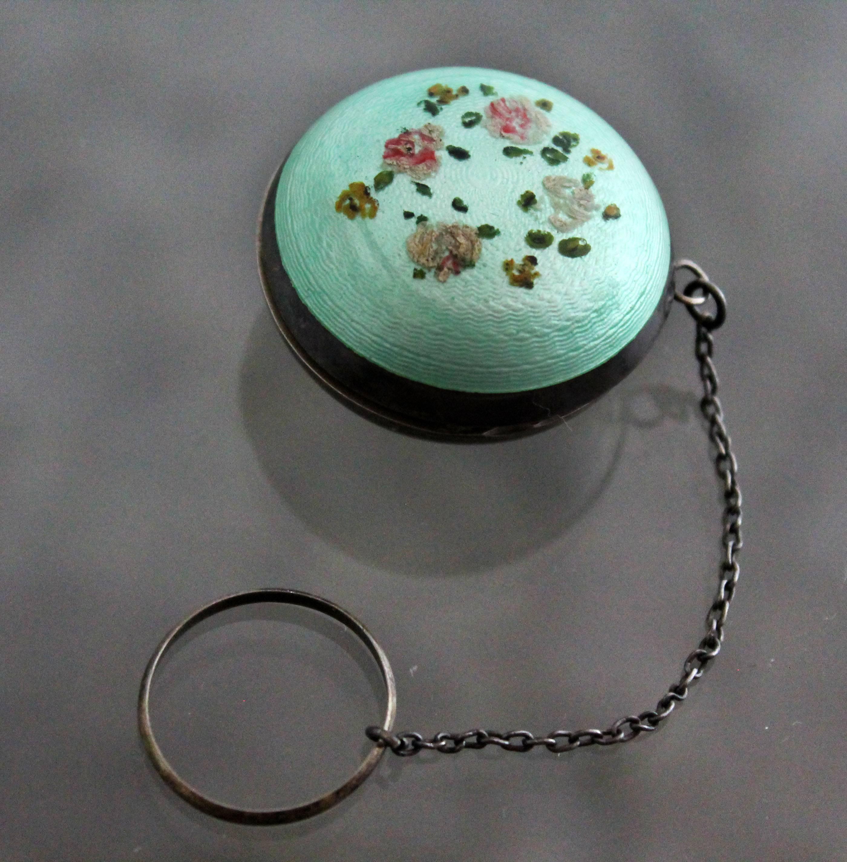 Art Deco turquoise guilloche and sterling chatelaine tiny ring compact with hand-painted flower design.

Perfect for primping! This somewhat ball-shaped guilloche enamel and sterling chatelaine style dance ring compact is turquoise or sea green and
