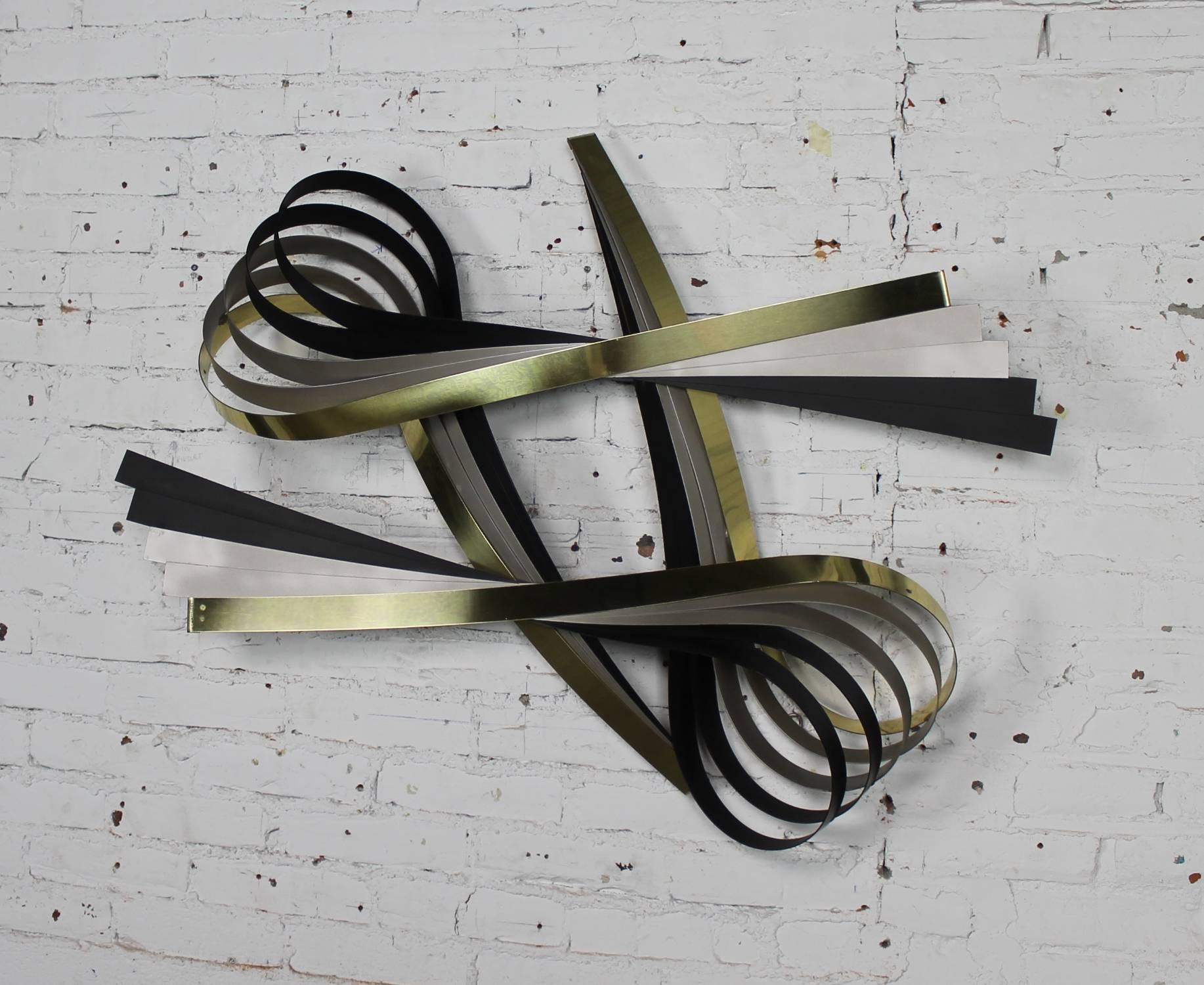 Awesome Curtis Jere wall sculpture in a ribbon design of brass-tone, silver and black painted metal. Signed C. Jere 1991 in wonderful vintage condition.

This incredible wall sculpture by Curtis Jere is just gorgeous. Its ribbons of brass-tone,