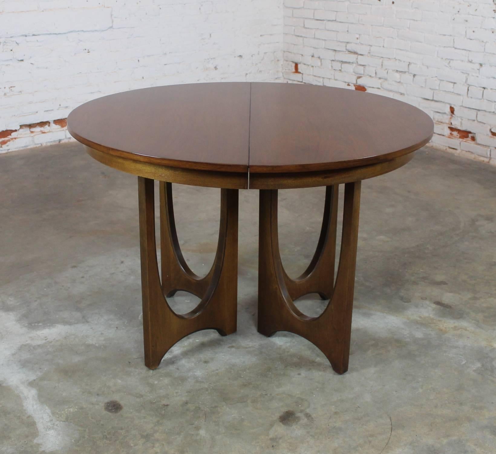 Absolutely wonderful Mid-Century Modern 6140-45 walnut dining table with three 12-inch leaves from the Brasilia collection by Broyhill Premier. This table is in very good condition. We even have its set of table pads.

If you are looking for a