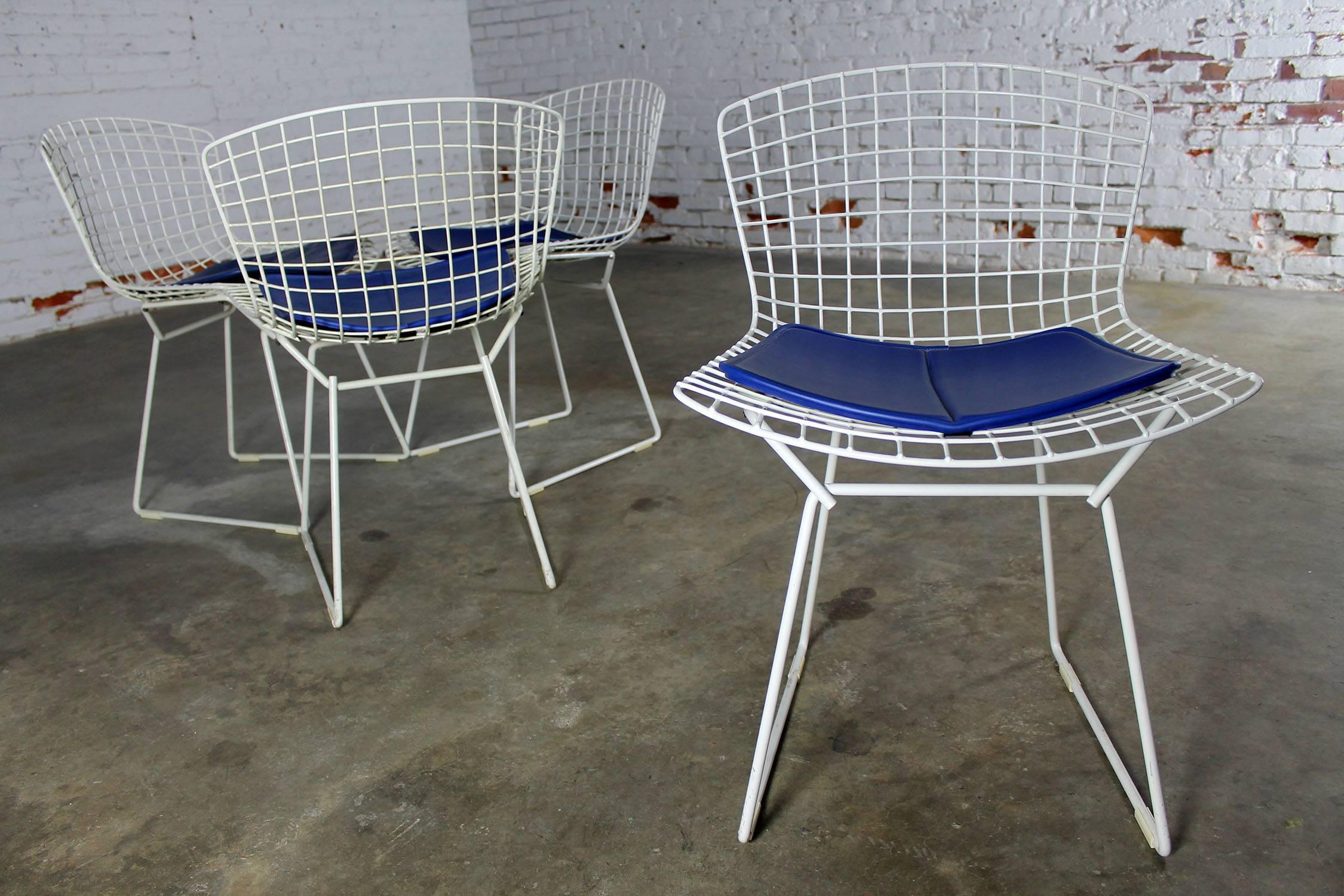 Classic Mid-Century Modern white wire Bertoia side chairs with blue seat pads. They are all in wonderful vintage condition. We haven’t seen any chipping or rust spots to the Rilsan coating. The white wire Bertoia side chair is one of the greatest