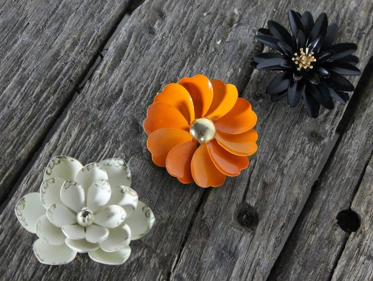 For you, a trio of vintage 1960s enamel flower brooches. One black and gold-tone crown Trifari daisy, a white unsigned gardenia, and an orange and gold-tone unsigned petal flower. They are in great vintage condition please see photos.

I couldn’t