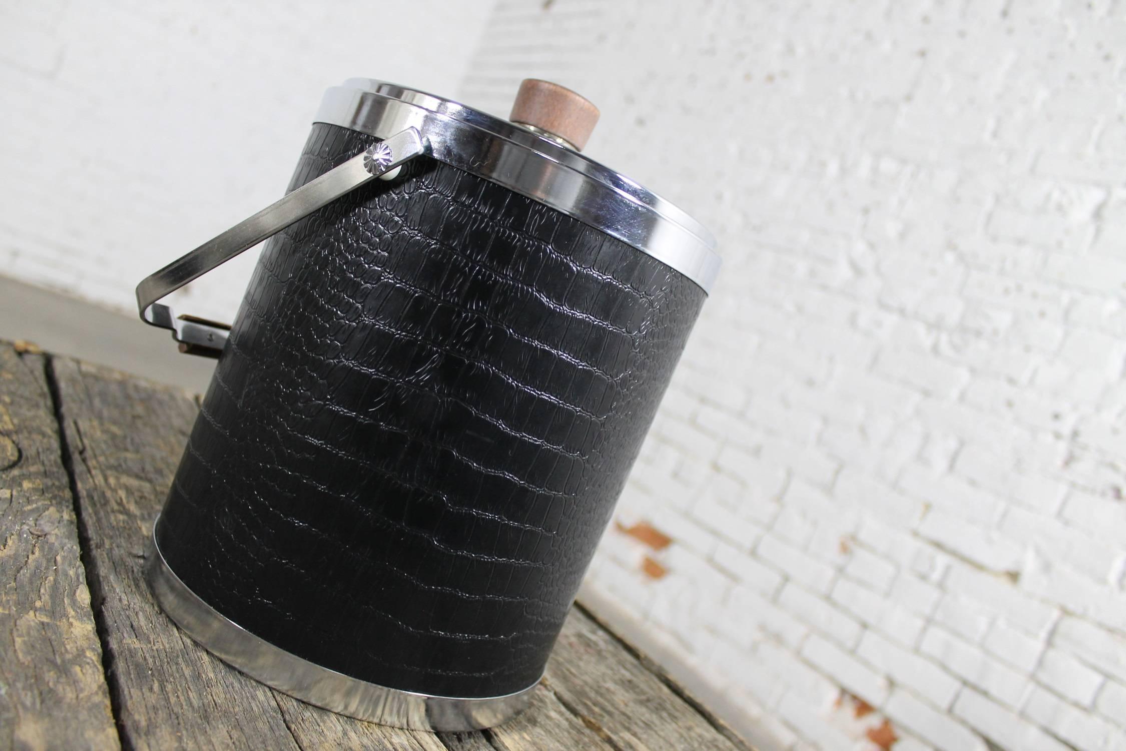 Handsome Mid-Century Modern ice bucket by Kromex covered in black faux alligator or crocodile with chrome trim and lid; and, wood knob and handle. In wonderful vintage condition and ready to use, circa 1960.

“See you later alligator, after while