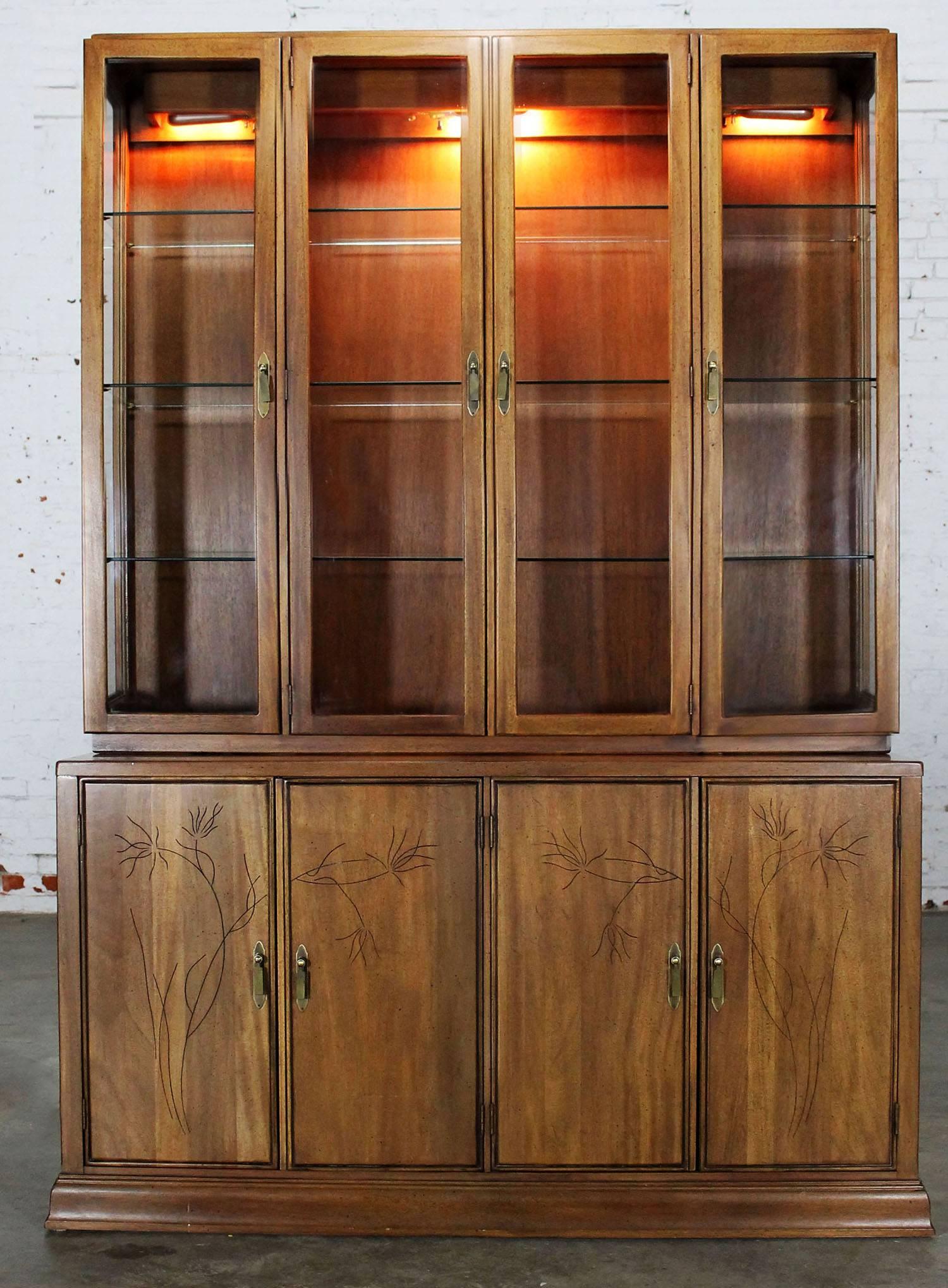 Gorgeous Mid-Century Modern, circa 1970 mahogany lighted display cabinet or china hutch with an incredibly beautiful and delicate almost Asian floral carving. In wonderful vintage condition with no outstanding flaws we have noticed.